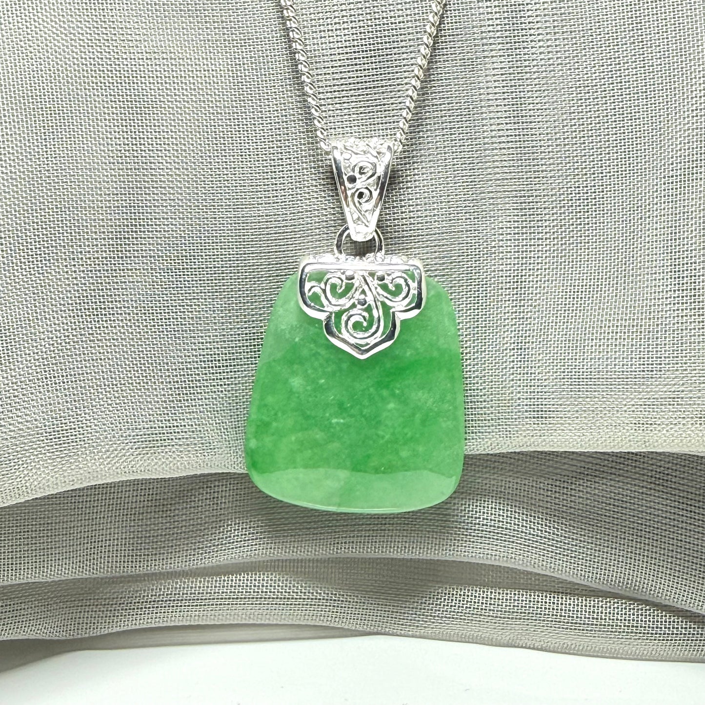 A real green jade necklace with a large shaped and patterned pendant