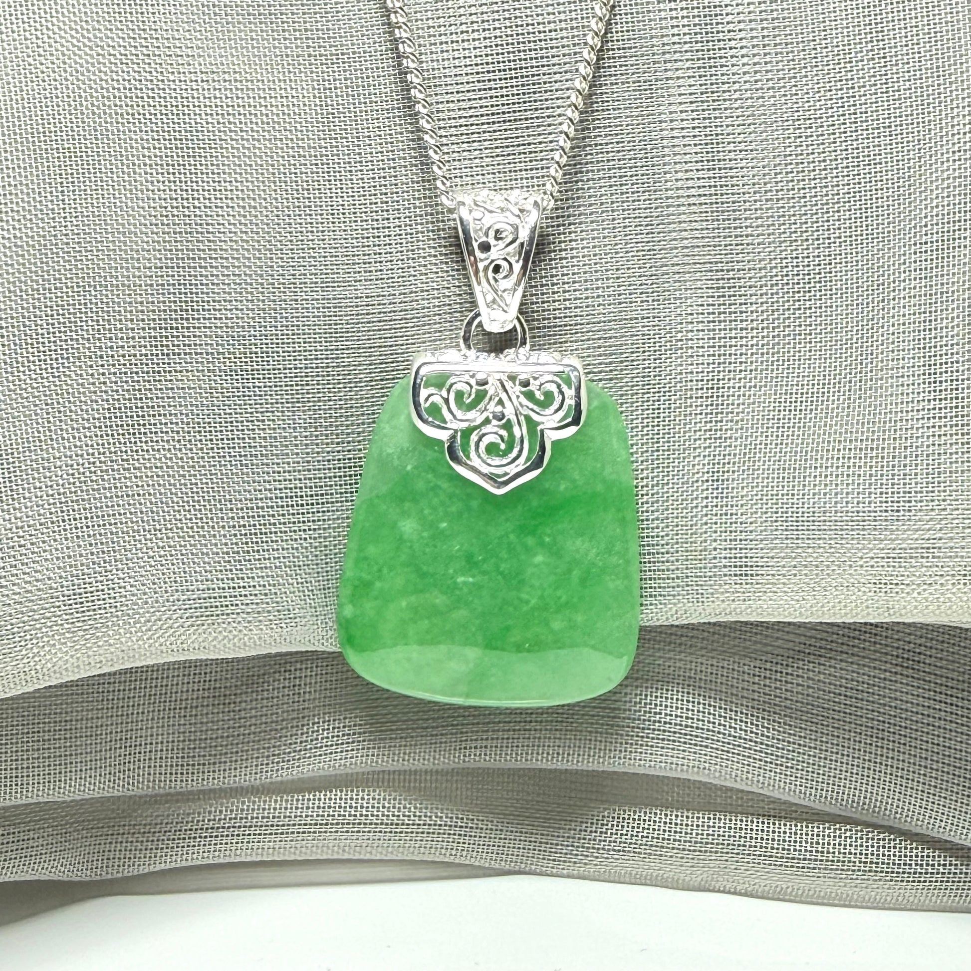 A real green jade necklace with a large shaped and patterned pendant