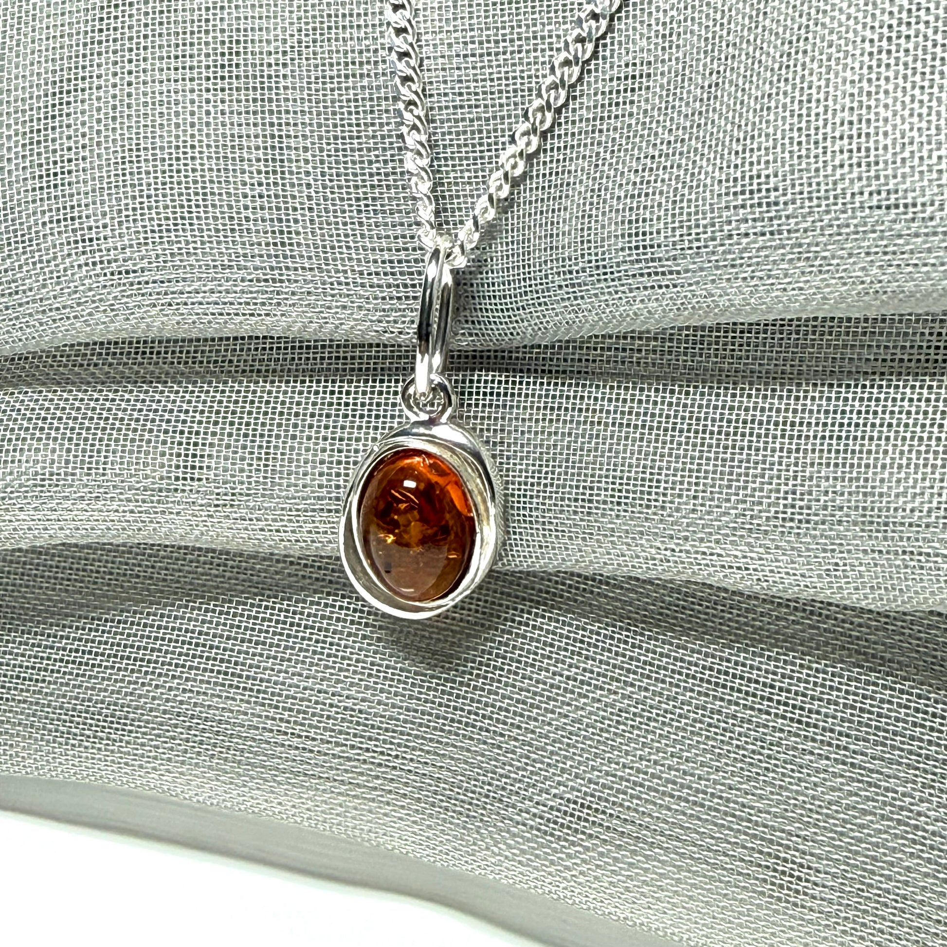 Orange real amber oval sterling silver necklace with a swirl set open pierced pendant