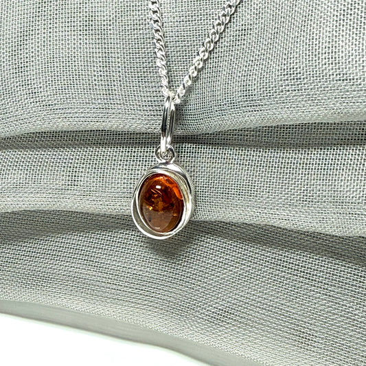 Orange real amber oval sterling silver necklace with a swirl set open pierced pendant