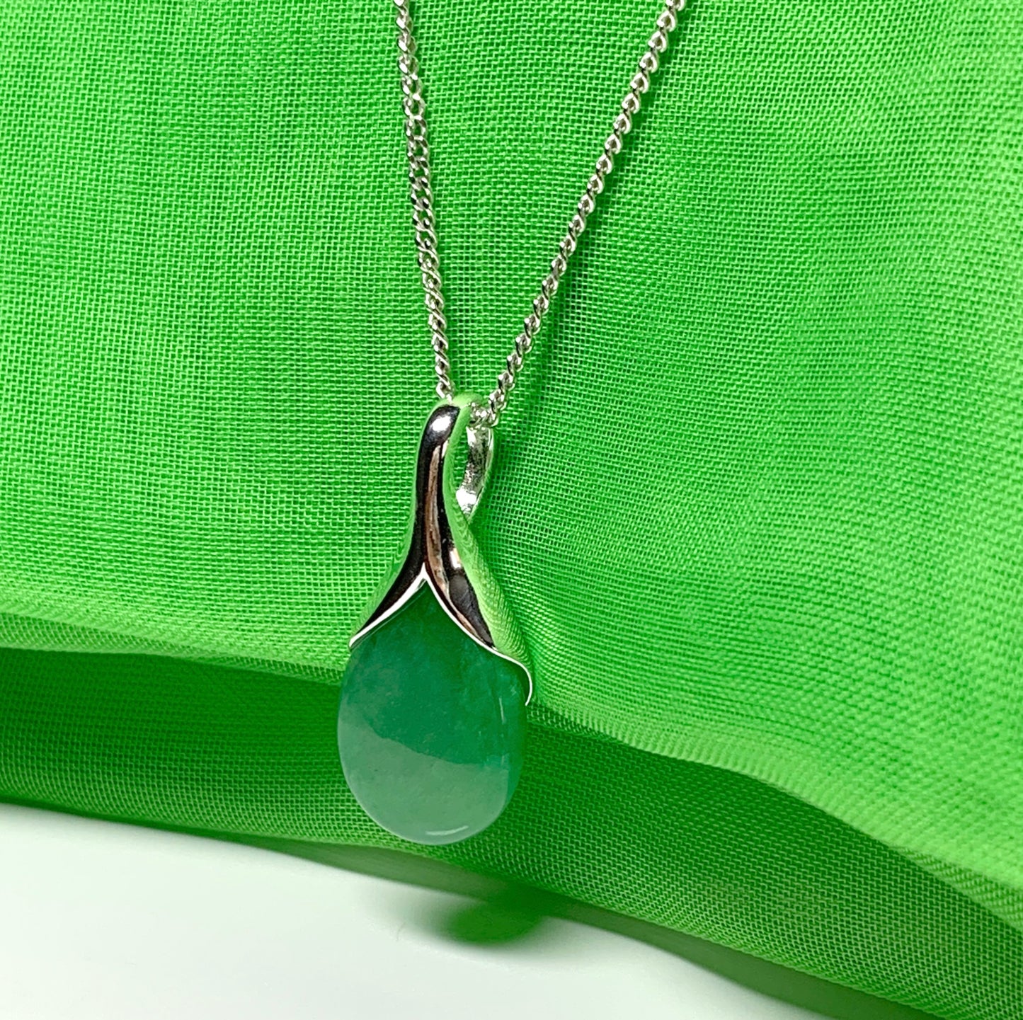 A real green jade pendant necklace in a teardrop shaped or pear shape