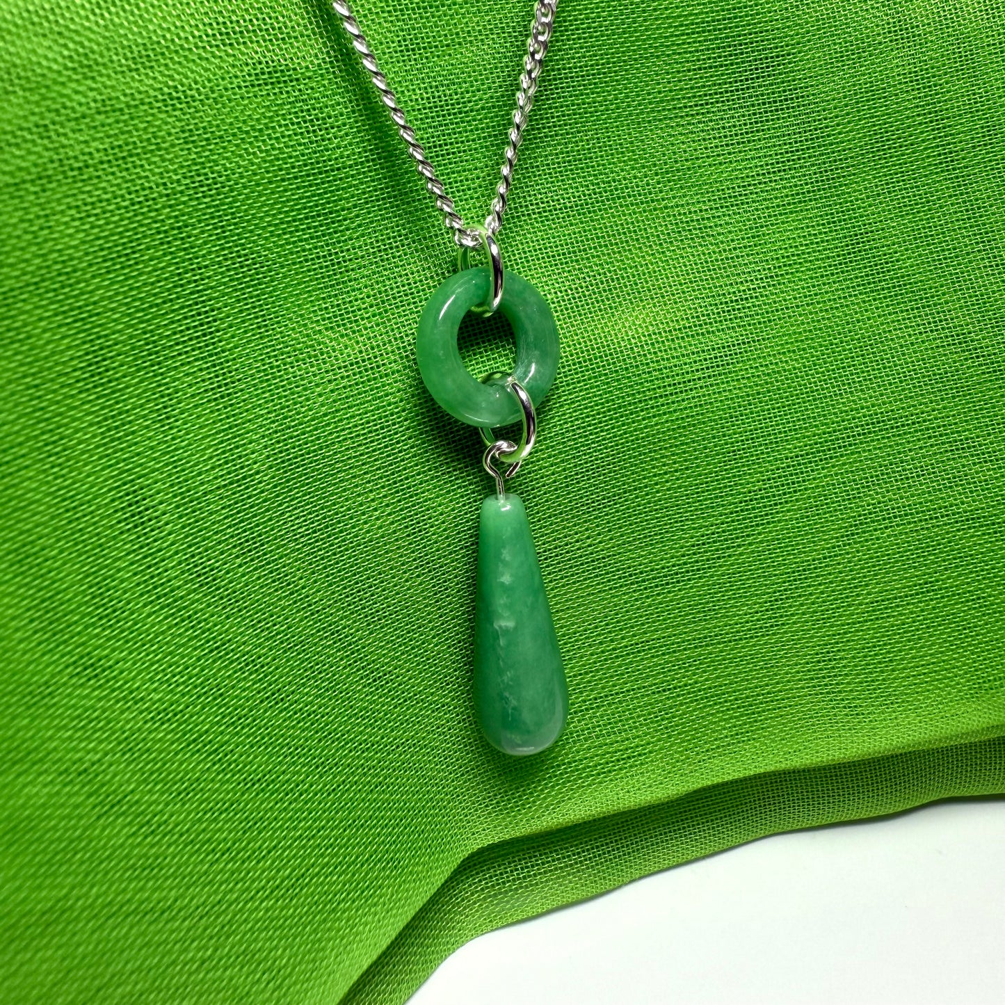 Necklace with green pendant on a green fabric background