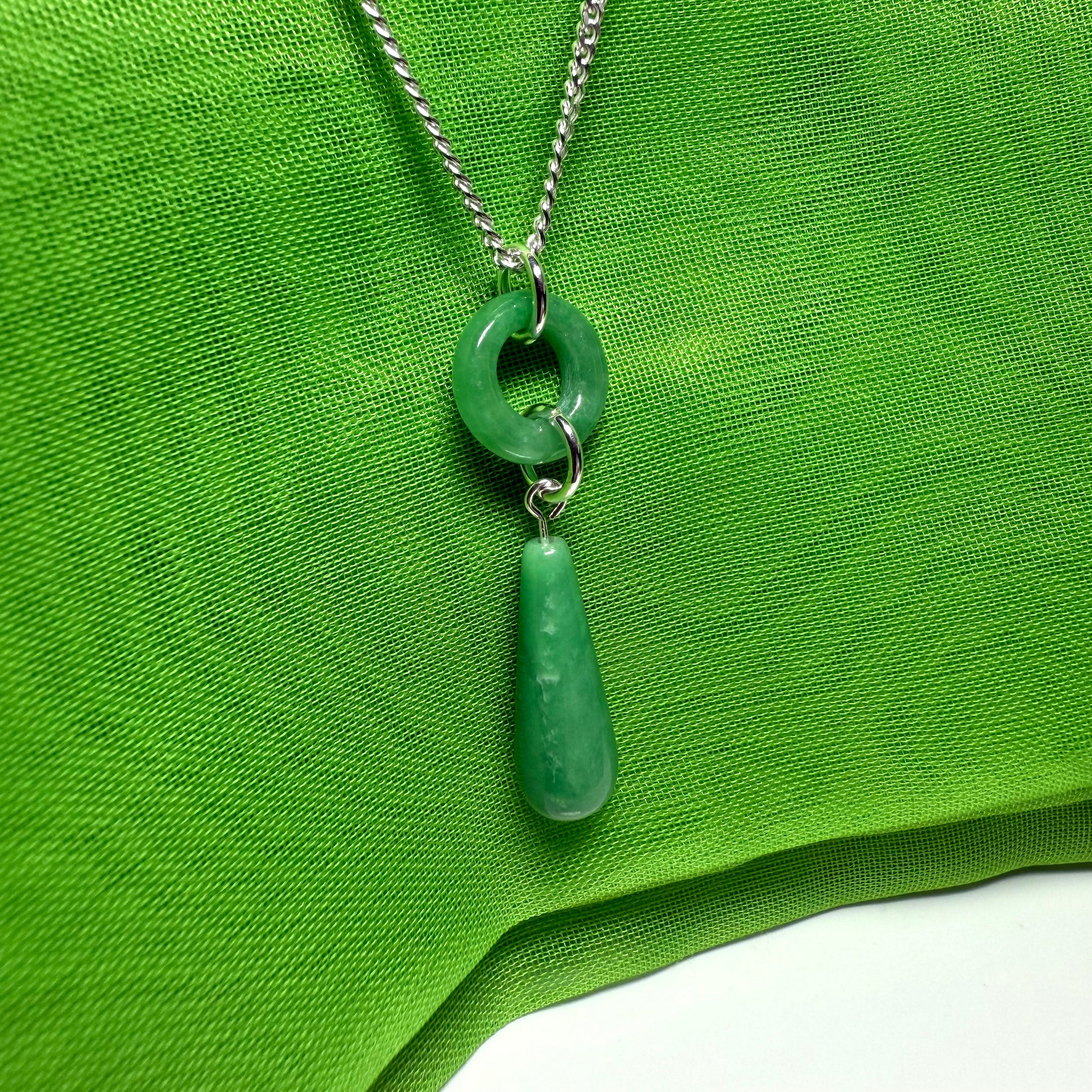 Necklace with green pendant on a green fabric background