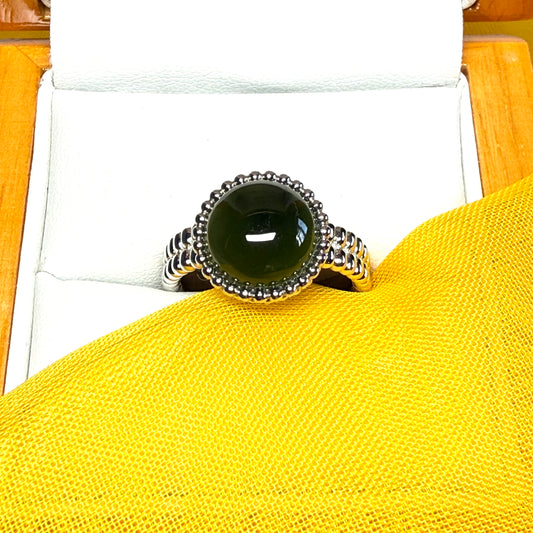 Silver ring with a black gemstone on a yellow surface