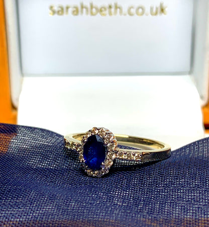 Dark blue sapphire diamond yellow gold oval cluster ring with diamond set shoulders