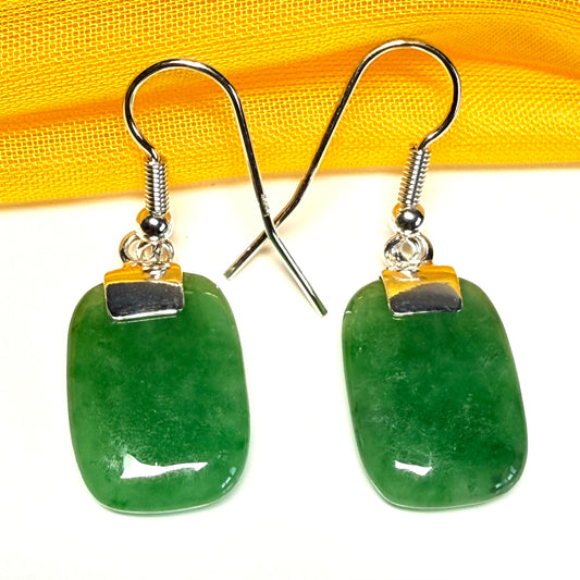 Green earrings with silver hooks on a white background
