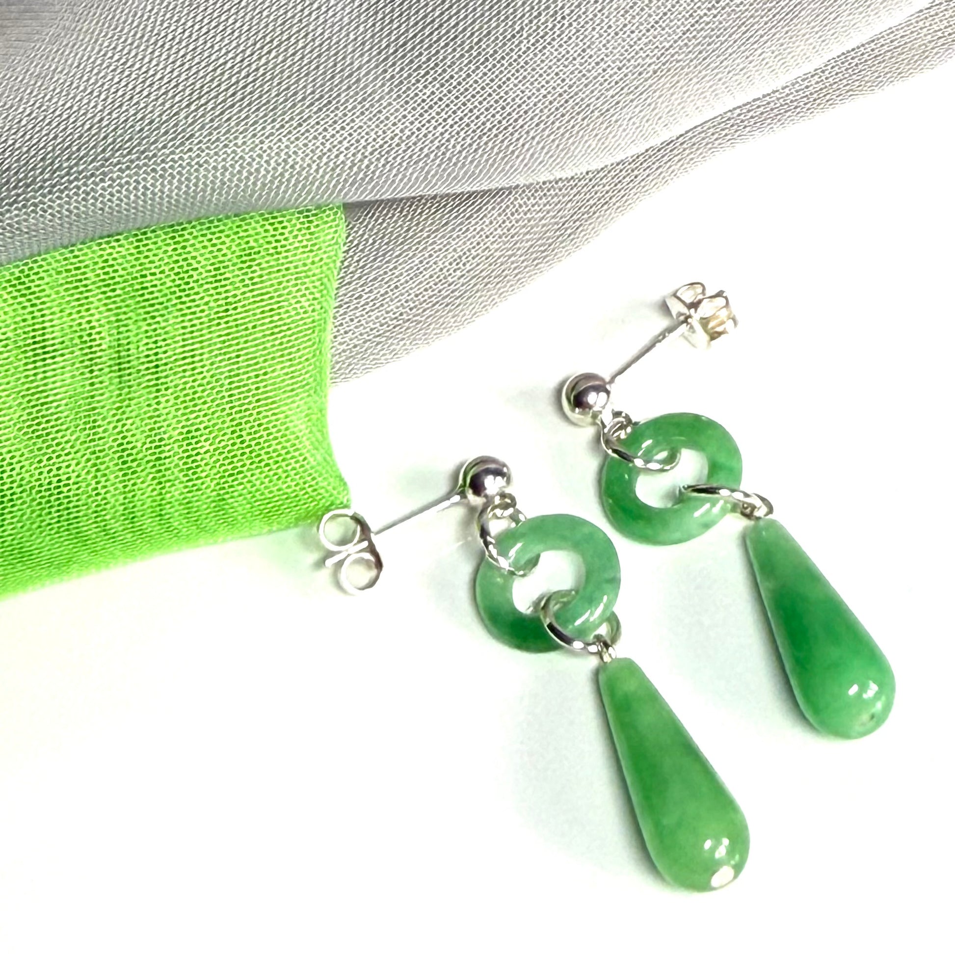 Green jade earrings with silver hooks on a white background