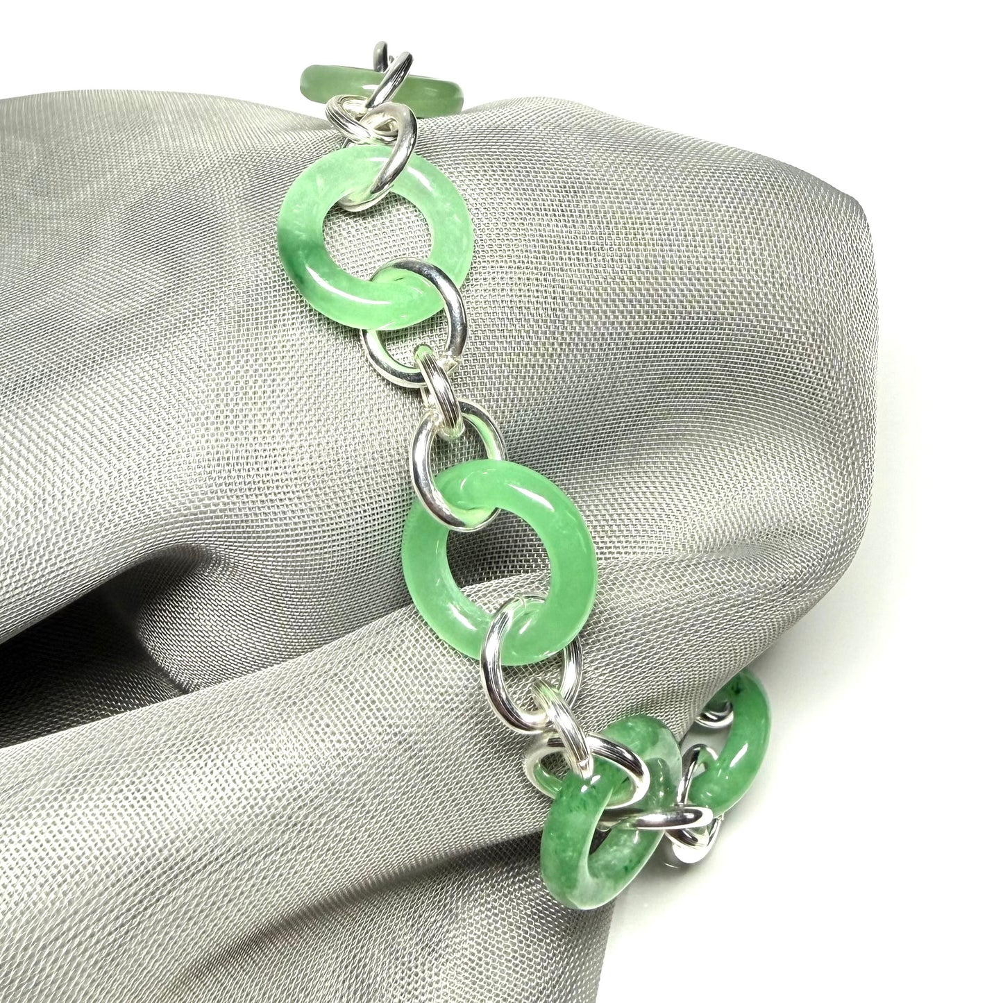 Green chain bracelet on a grey fabric surface