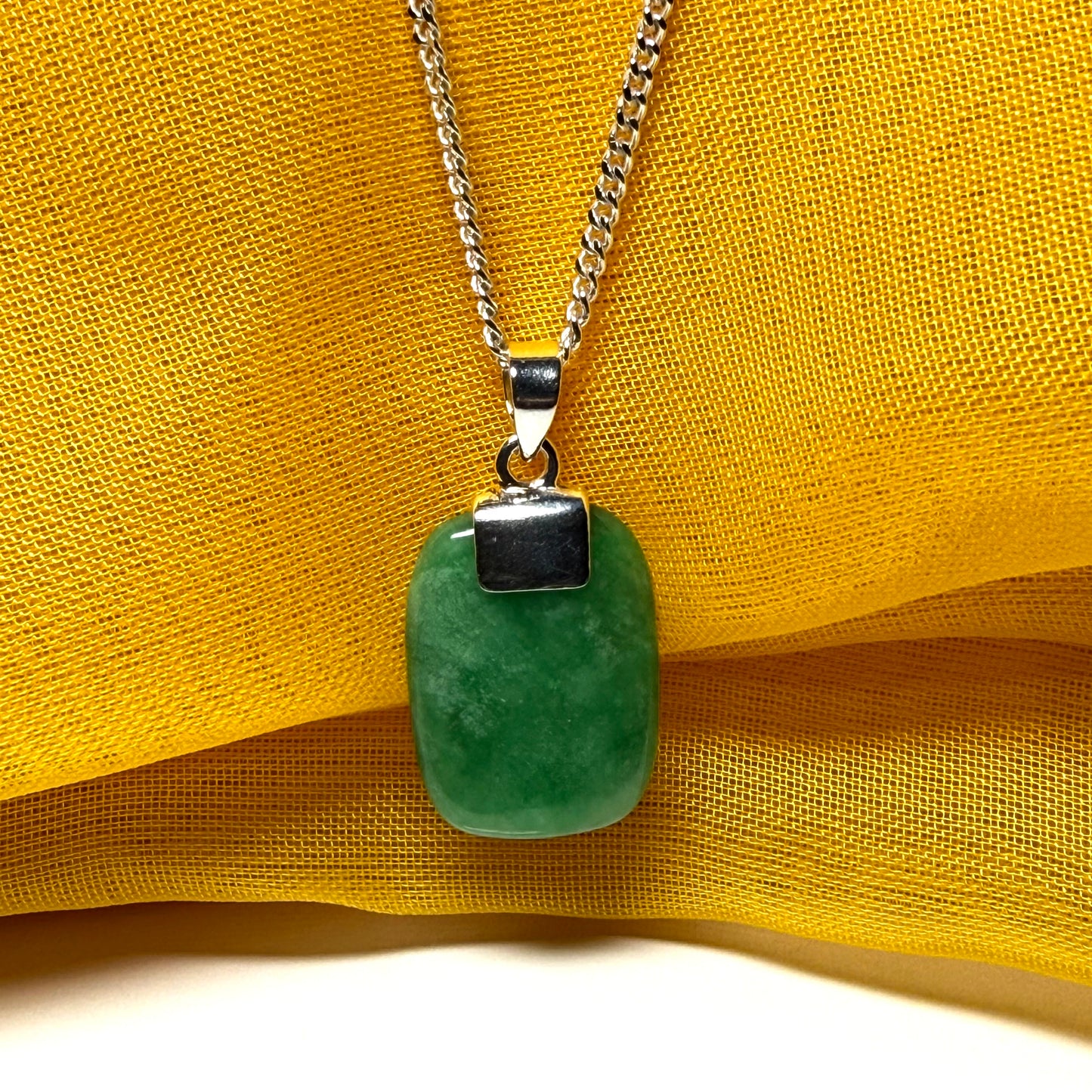 Green pendant necklace on a yellow fabric background