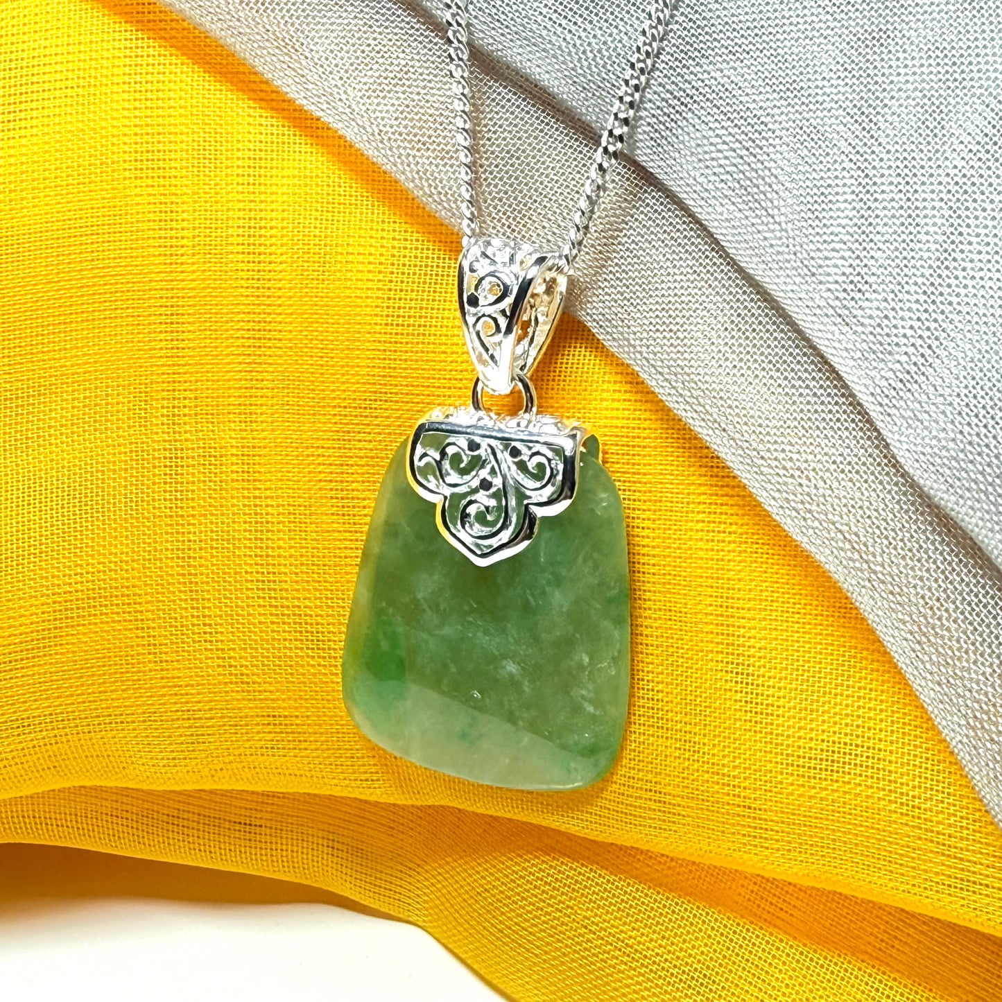 A green real jade necklace with a large shaped and patterned pendant with a chain