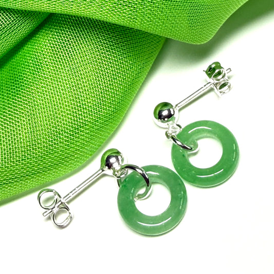 Green hoop earrings with silver hooks on a green fabric background