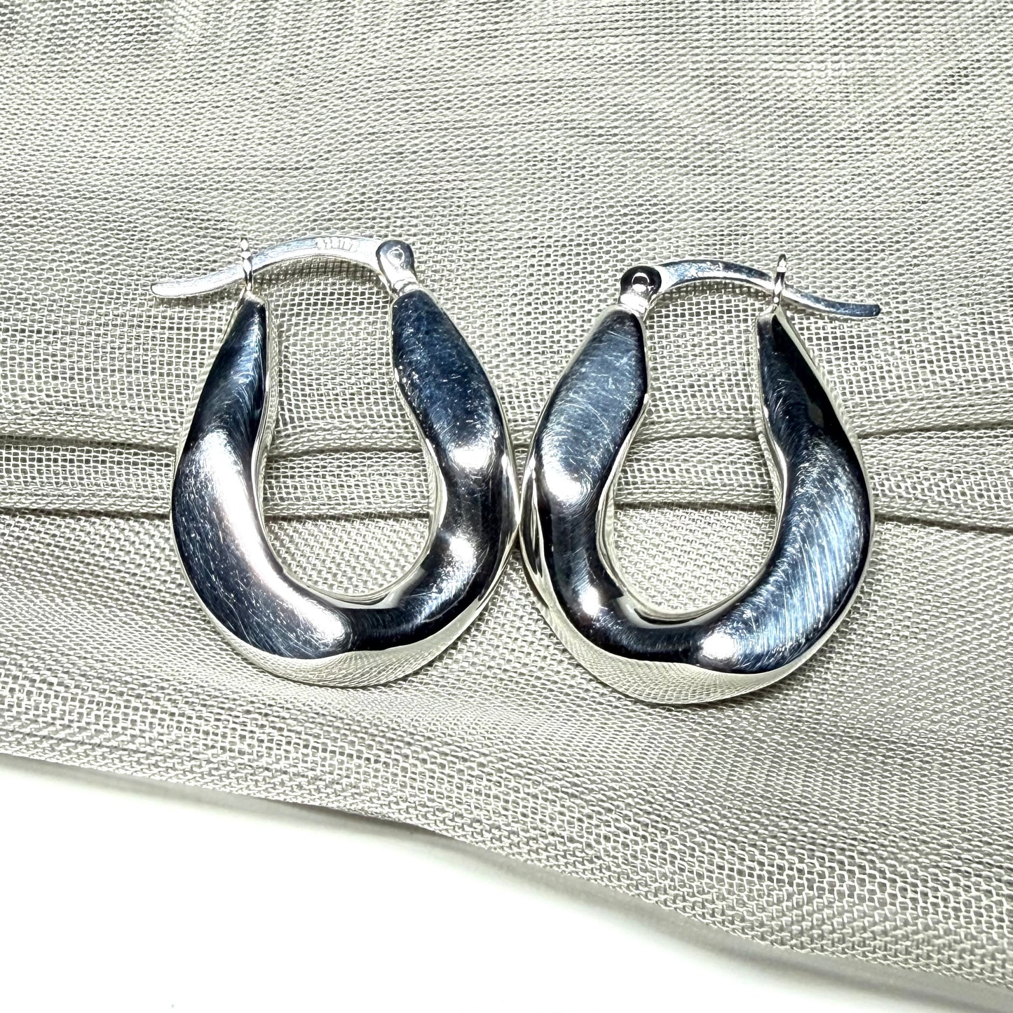 Hoop earrings made in shimmering sterling silver with a fancy twisted design to them