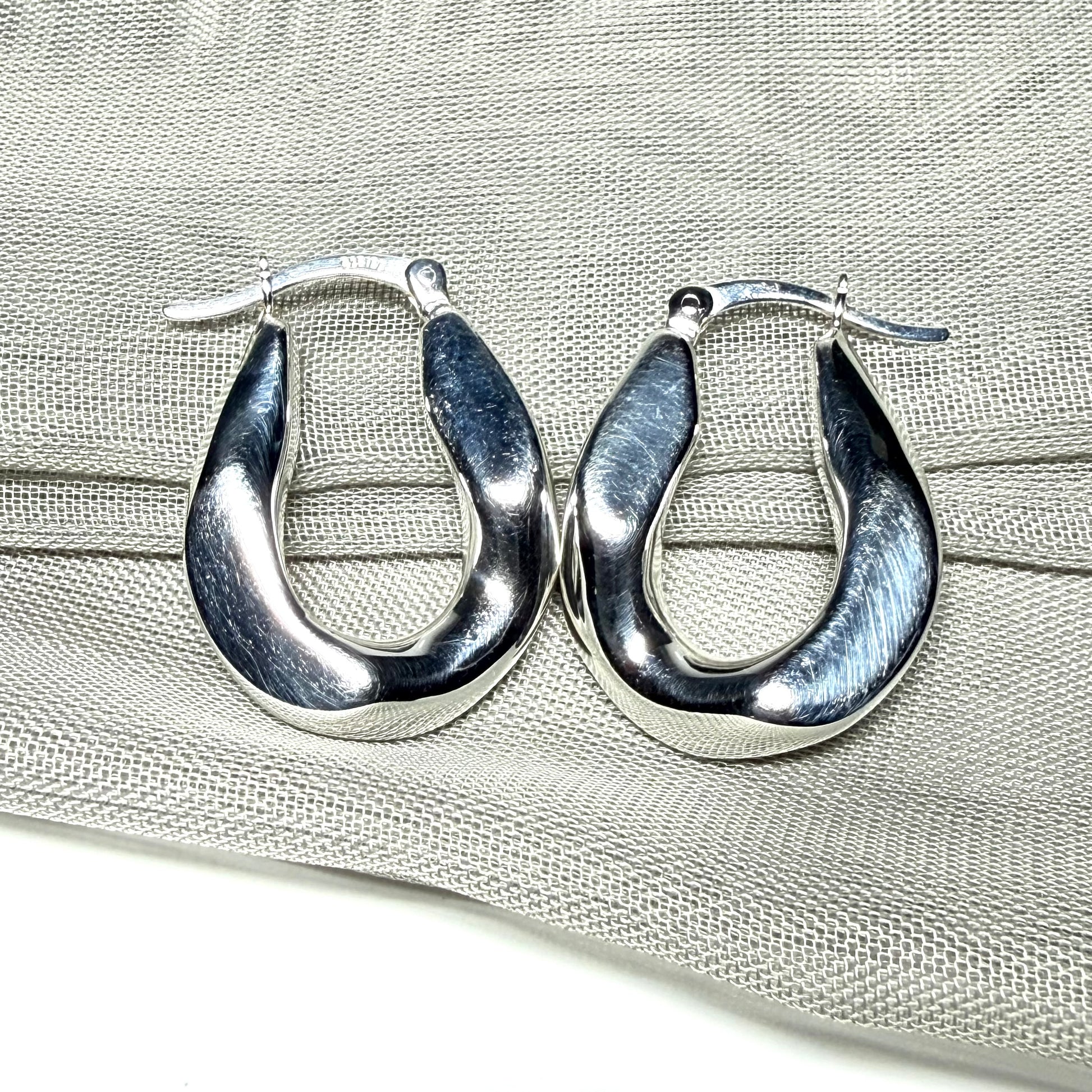 Hoop earrings made in shimmering sterling silver with a fancy twisted design to them