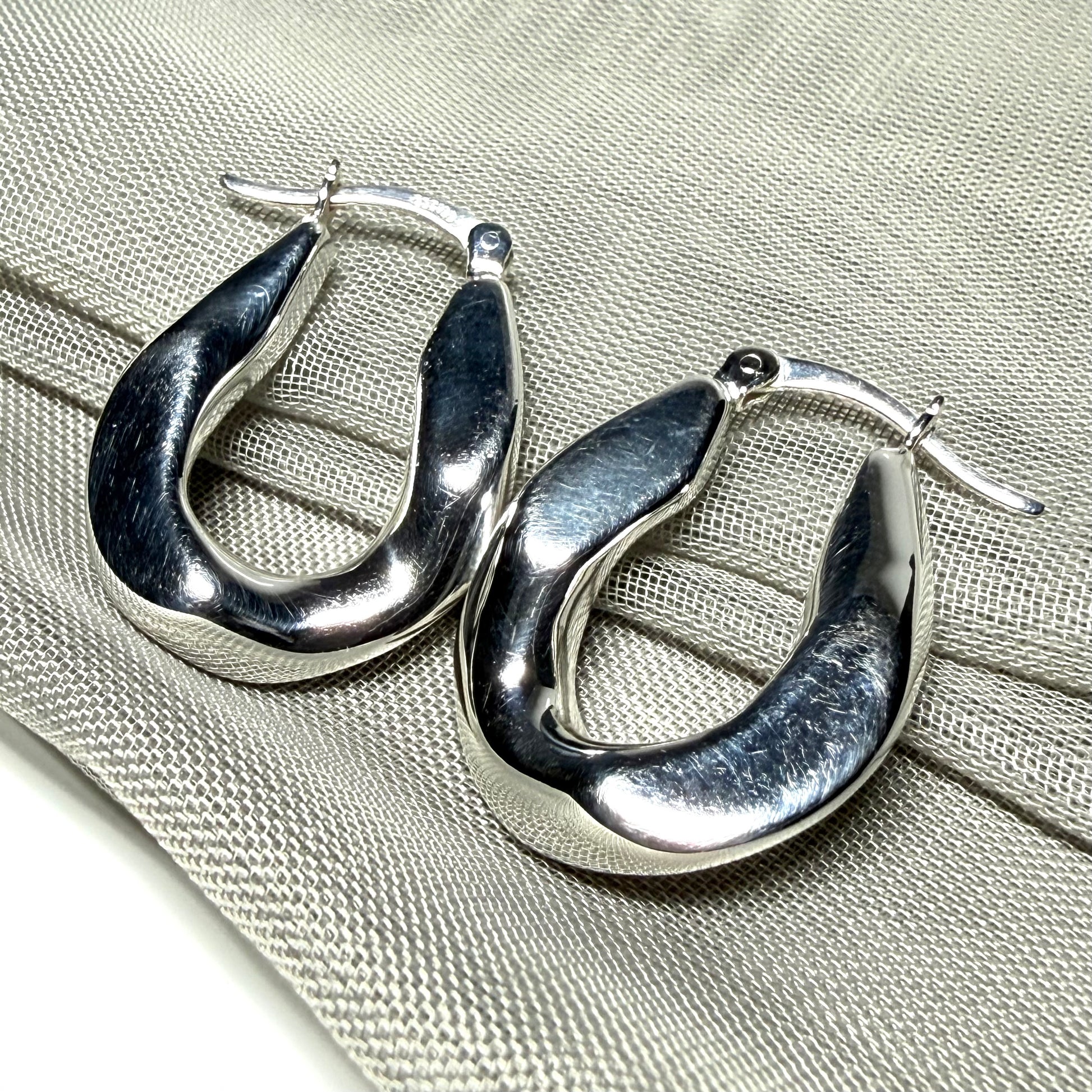 Hoop earrings made in shimmering sterling silver with a fancy twisted design to them