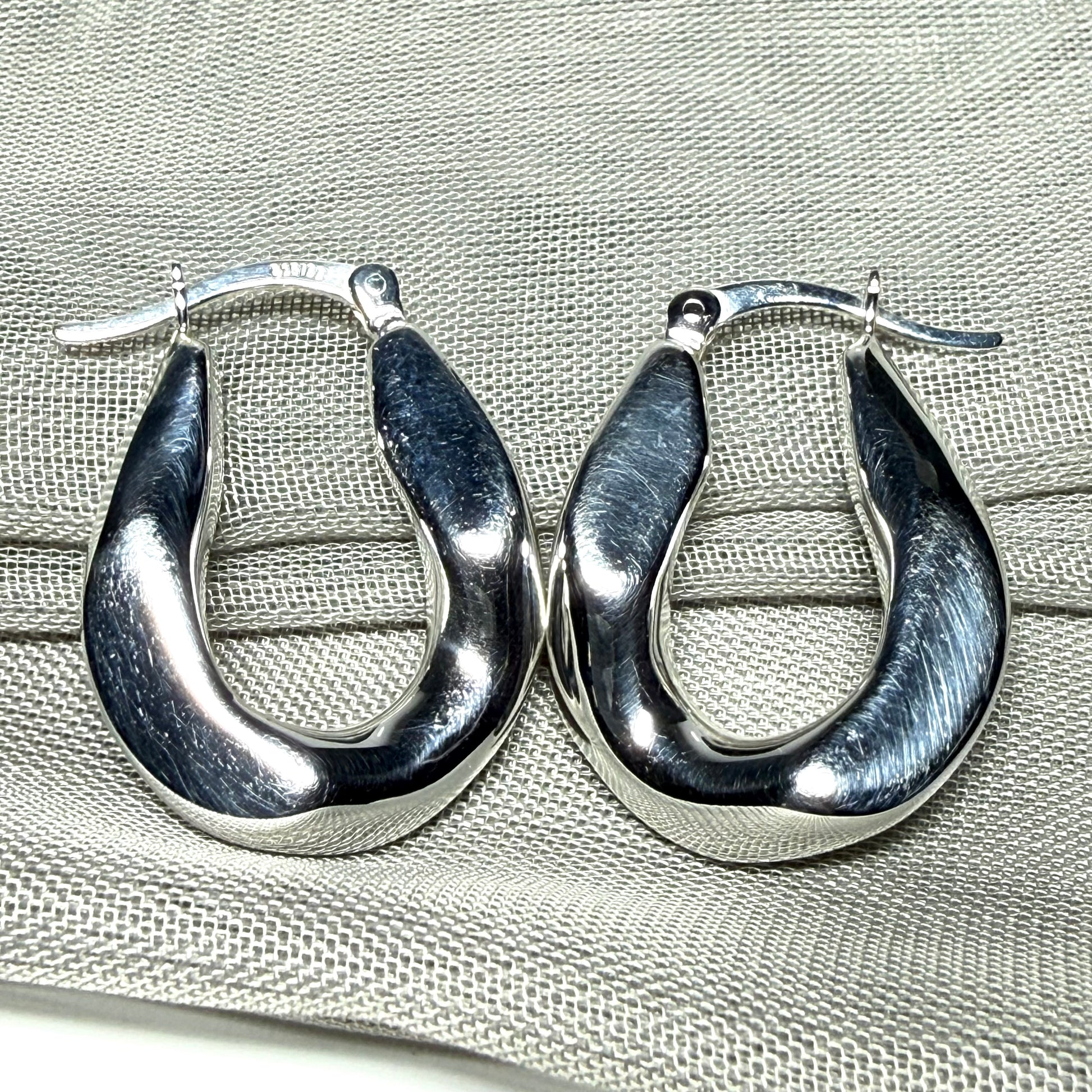 Hoop earrings made in shimmering sterling silver with a fancy twisted design to them