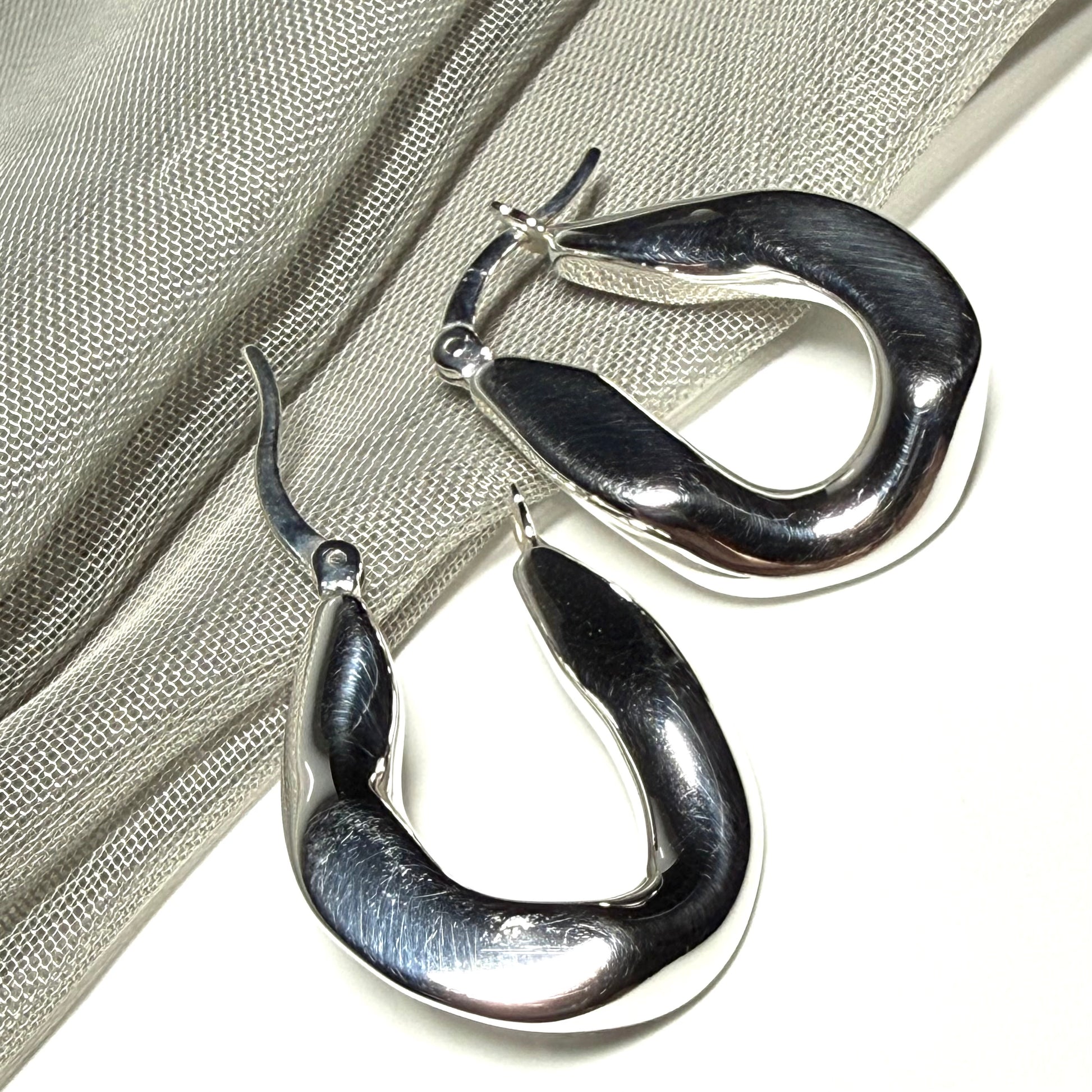 Hoop earrings made in shimmering sterling silver with a fancy twisted design to them