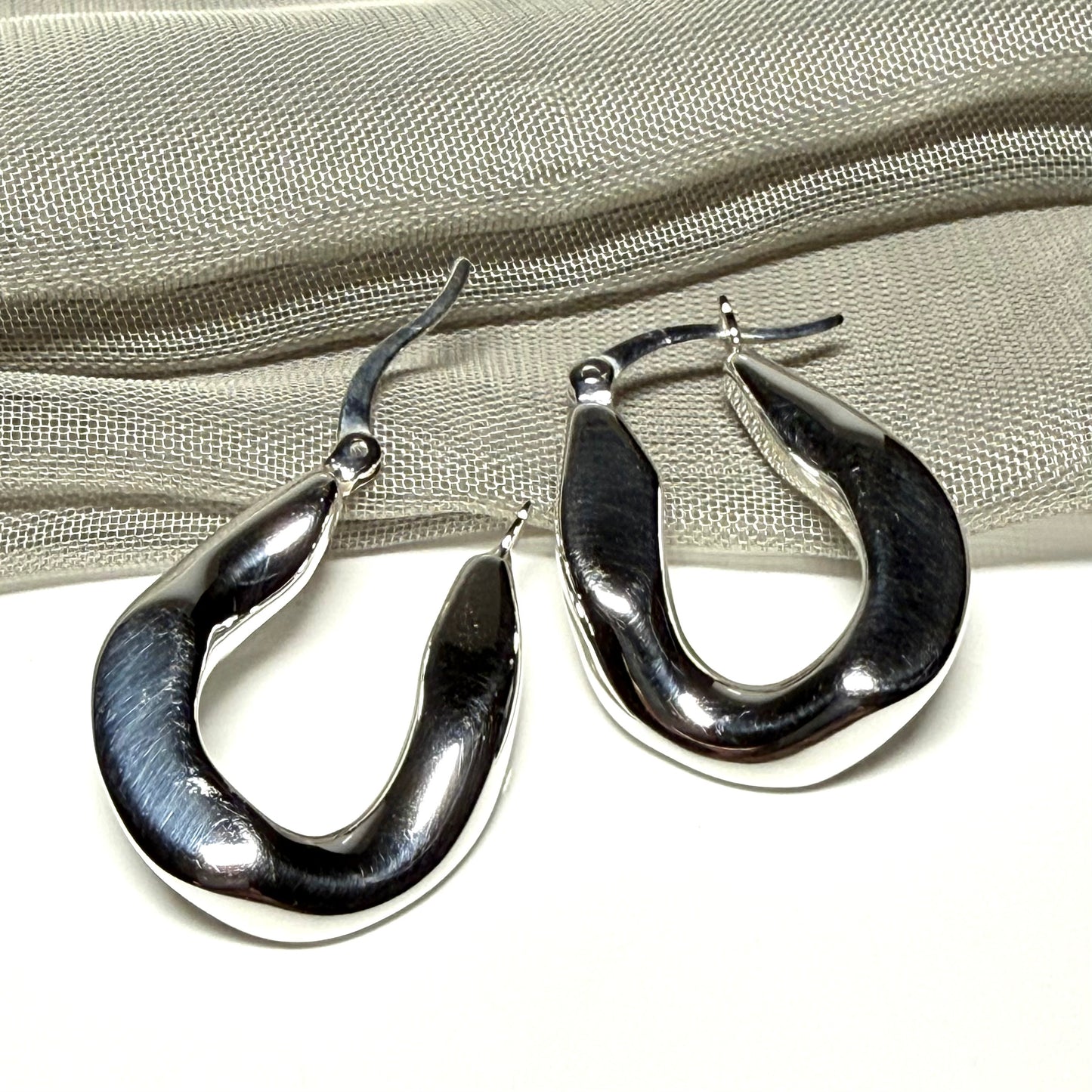 Hoop earrings made in shimmering sterling silver with a fancy twisted design to them