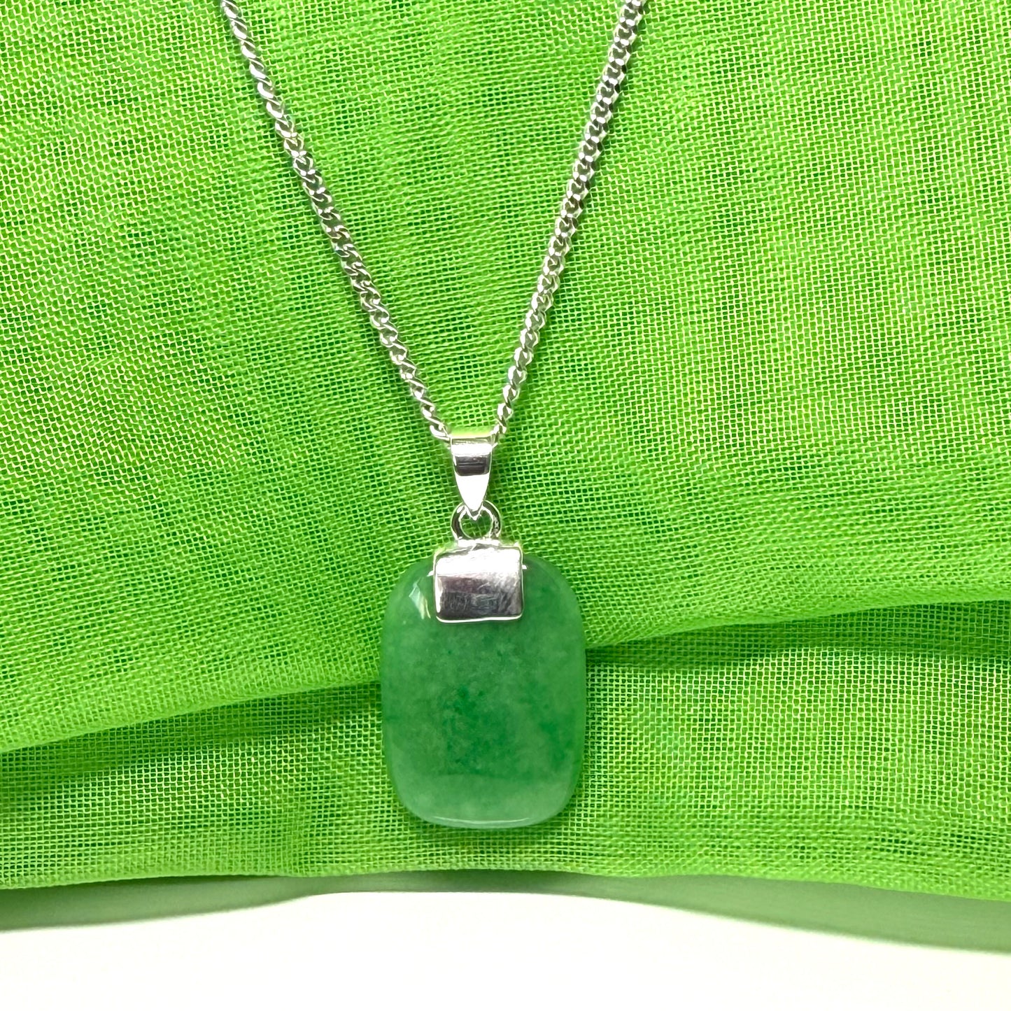 A necklace pendant having a real green jade sterling silver cushion shaped