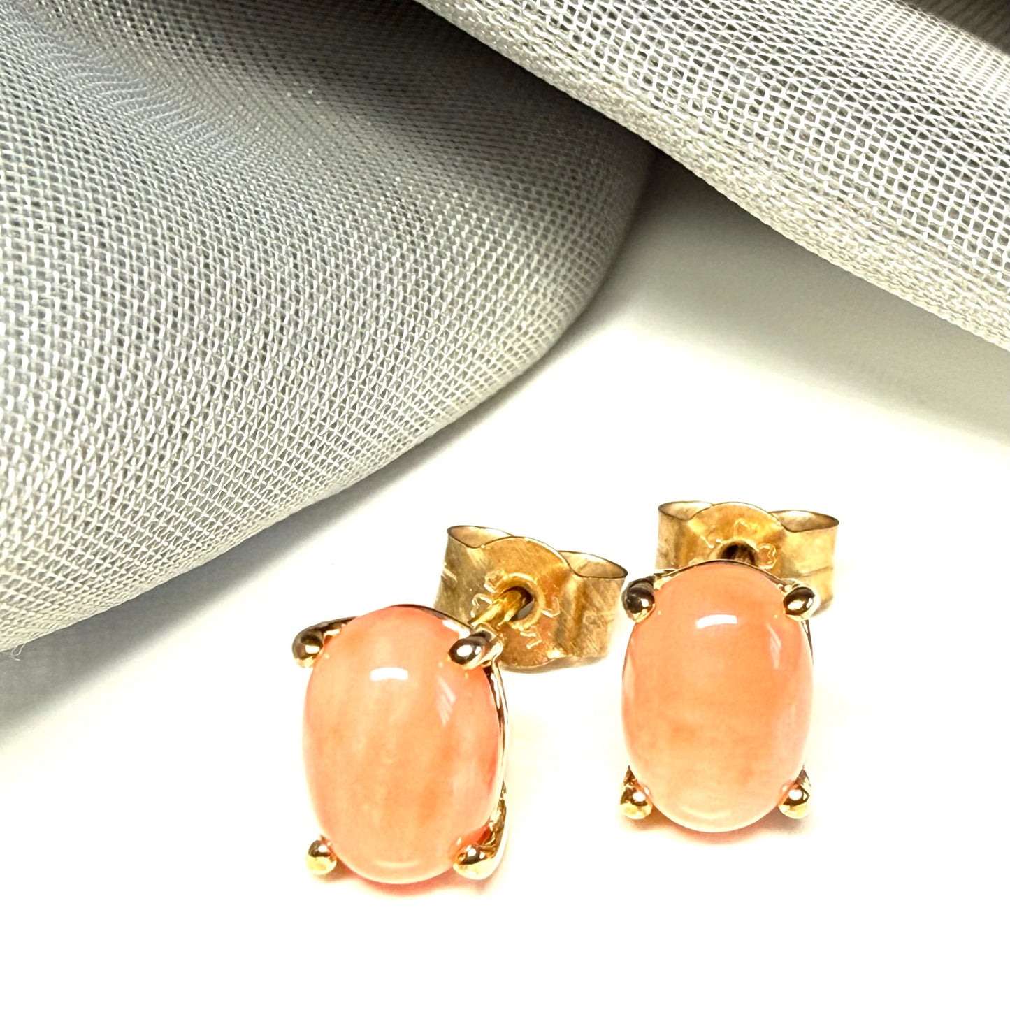 A pair of real coral oval shaped stud earrings yellow gold claw set
