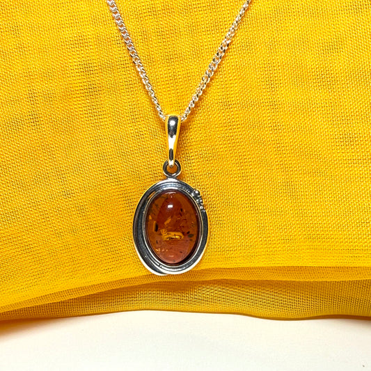 Orange real amber oval sterling silver necklace with a swirl set pendant