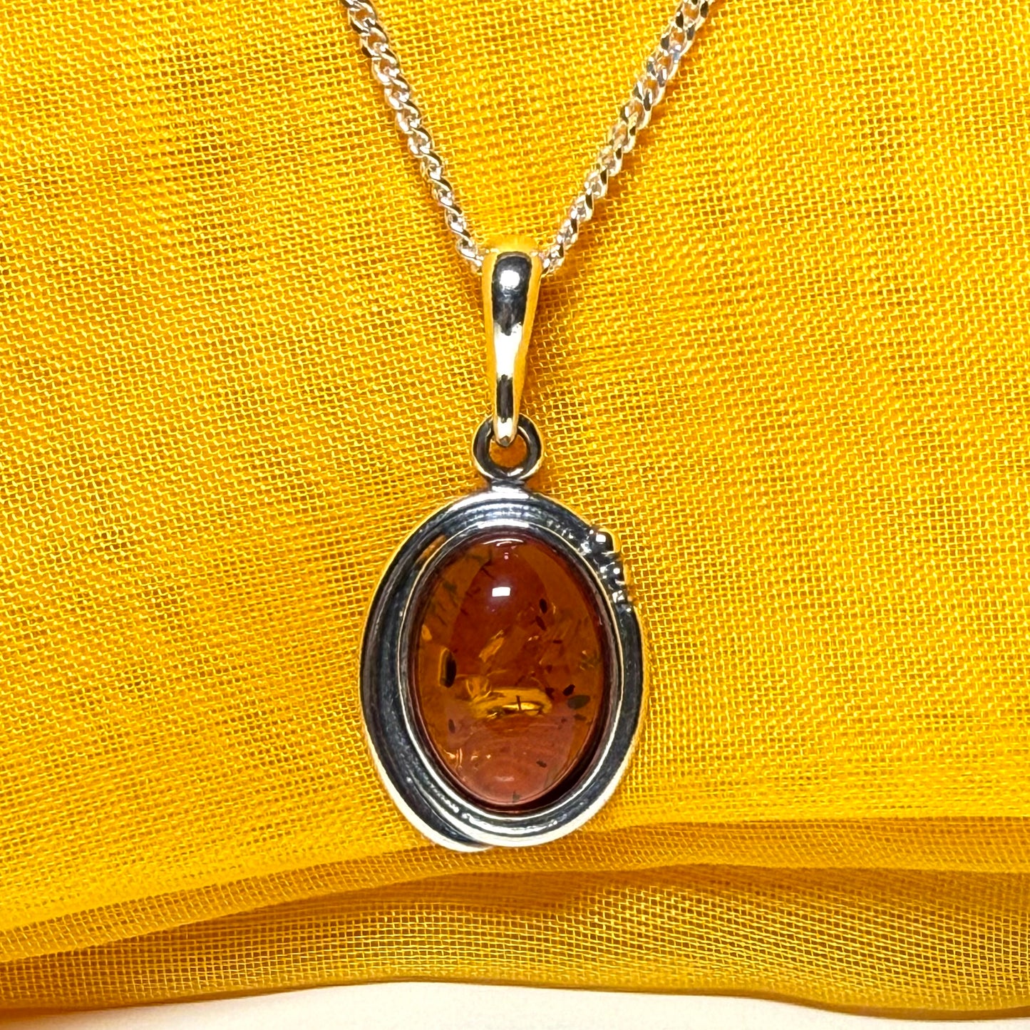 Orange real amber oval sterling silver necklace with a swirl set pendant