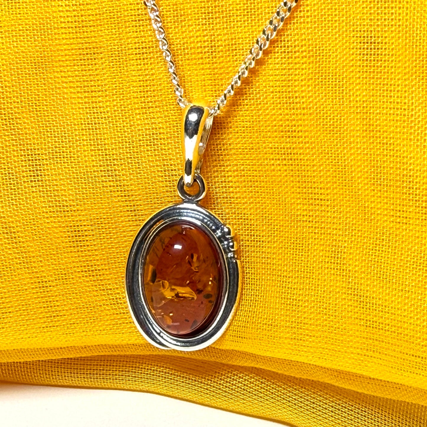 Orange real amber oval sterling silver necklace with a swirl set pendant