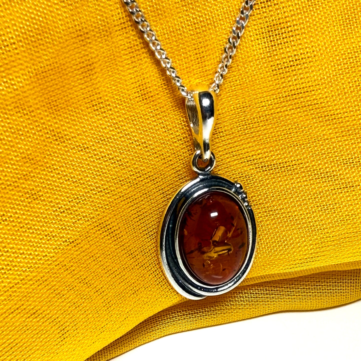 Orange real amber oval sterling silver necklace with a swirl set pendant