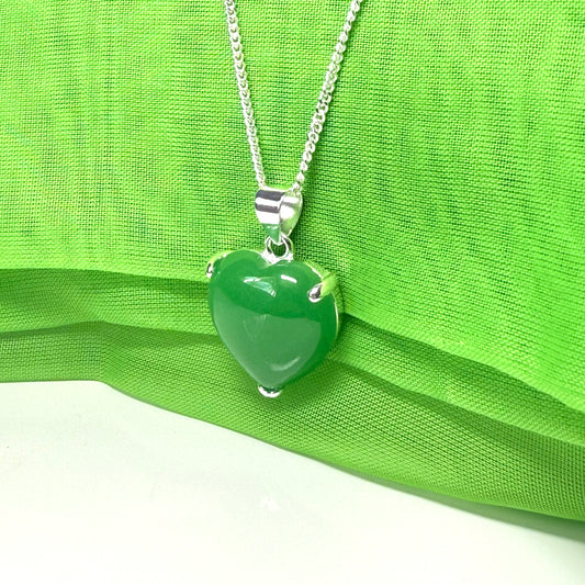 Green heart-shaped pendant on a silver chain against a green fabric background