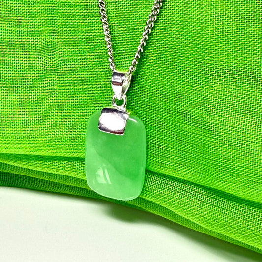 Green sea glass pendant on a silver chain against a green fabric background