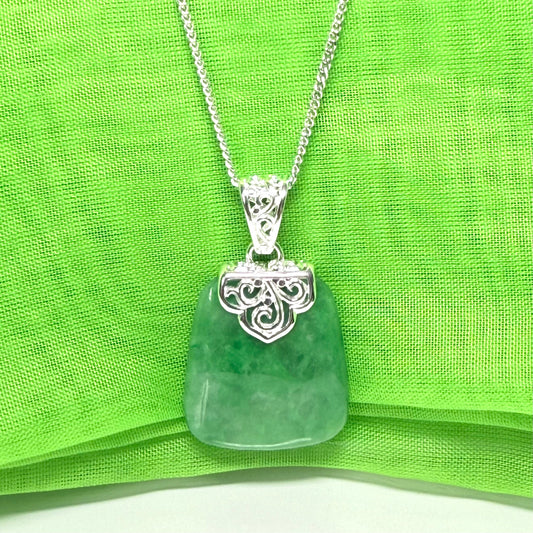 Green real jade pendant necklace on a green fabric background
