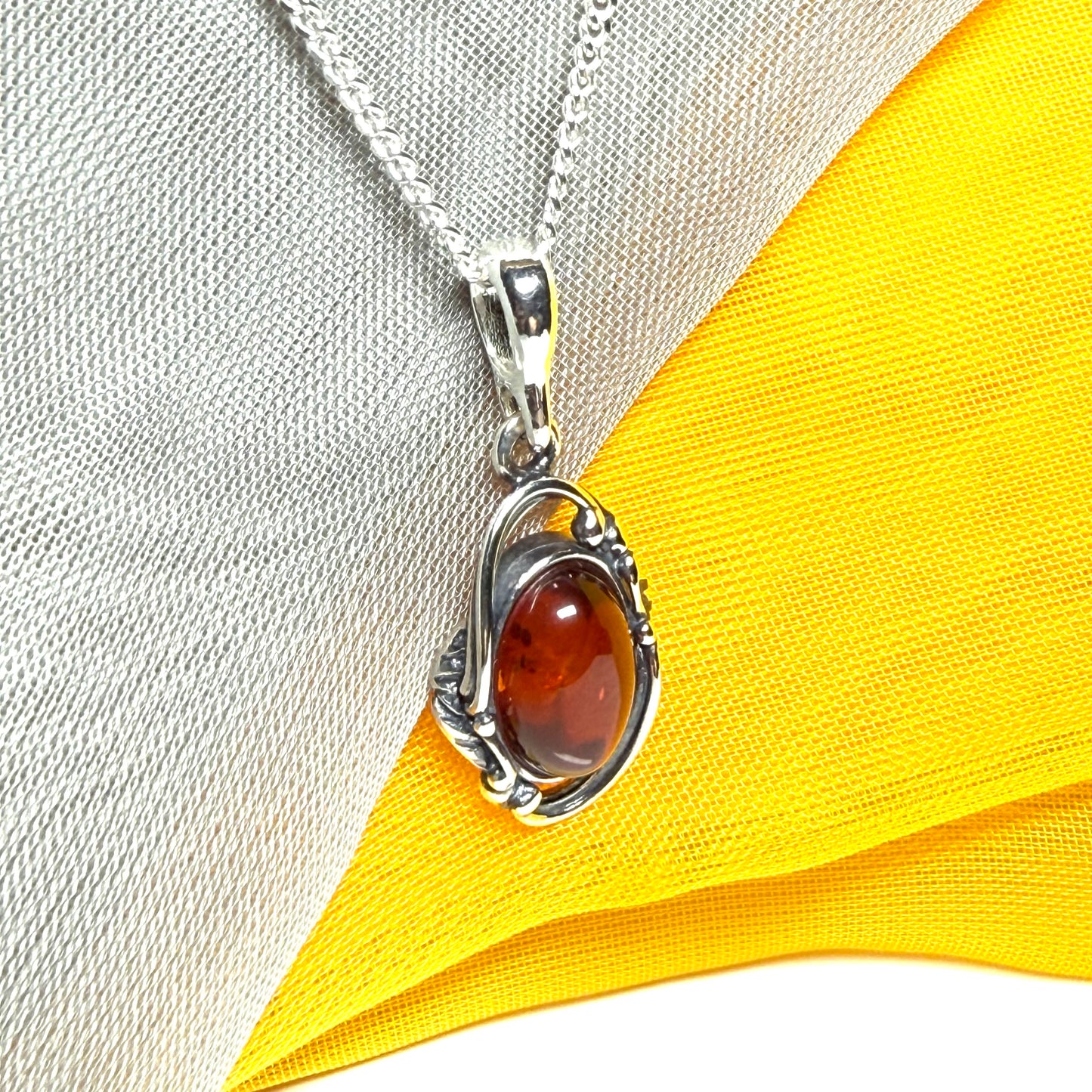 Orange real amber oval sterling silver necklace with a swirl set open pendant