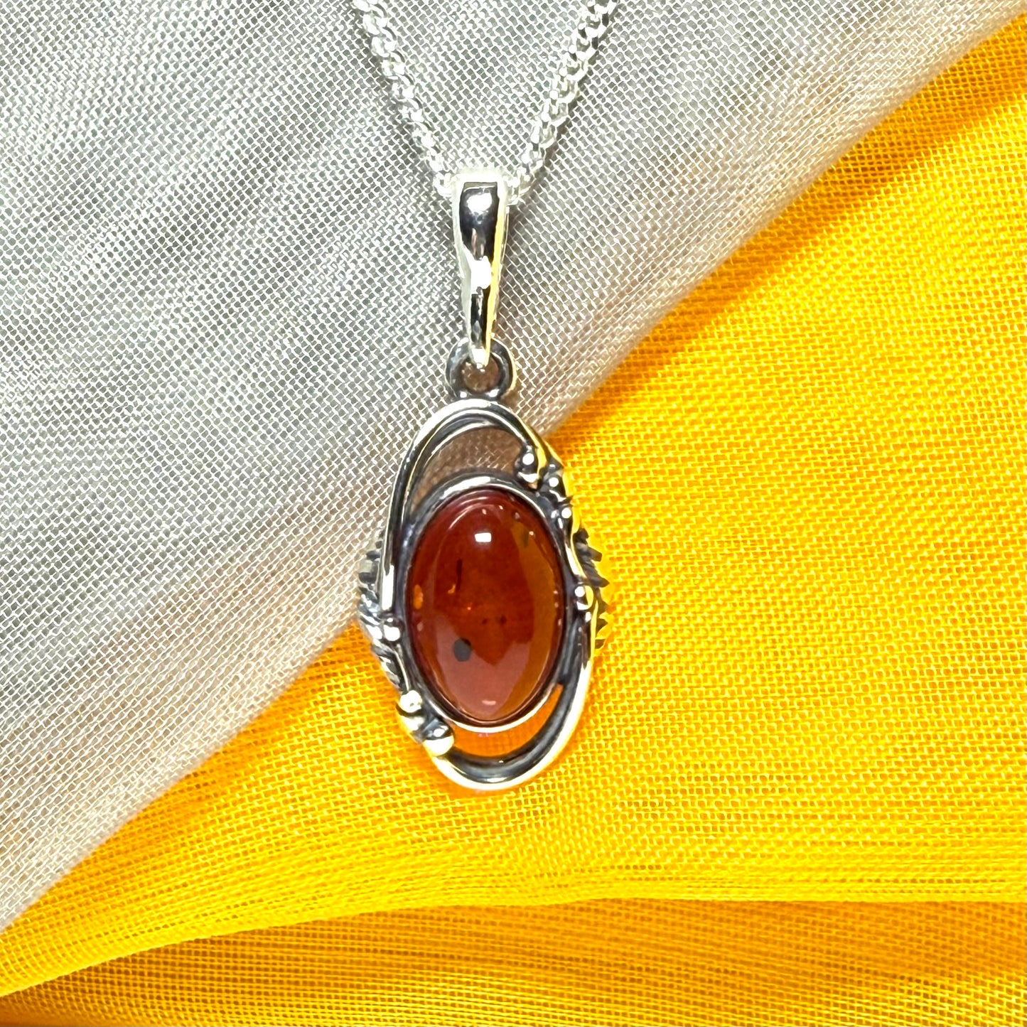Orange real amber oval sterling silver necklace with a swirl set open pendant
