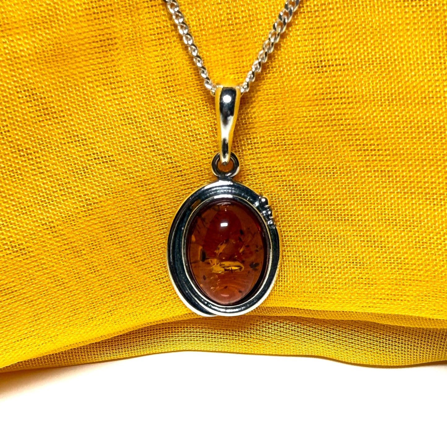 Orange real amber oval sterling silver necklace with a swirl set pendant