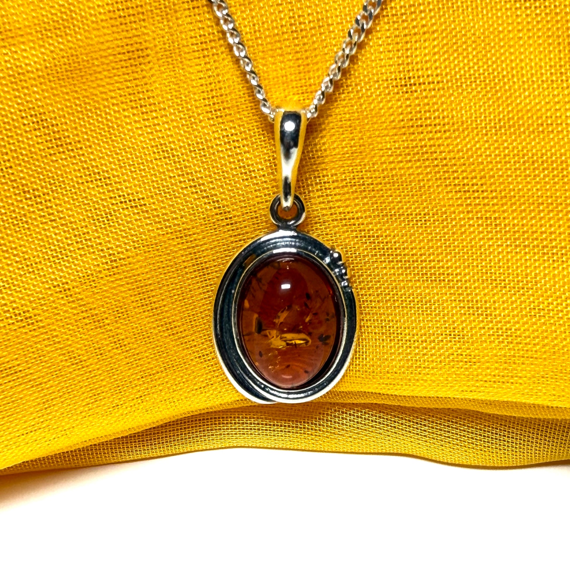 Orange real amber oval sterling silver necklace with a swirl set pendant