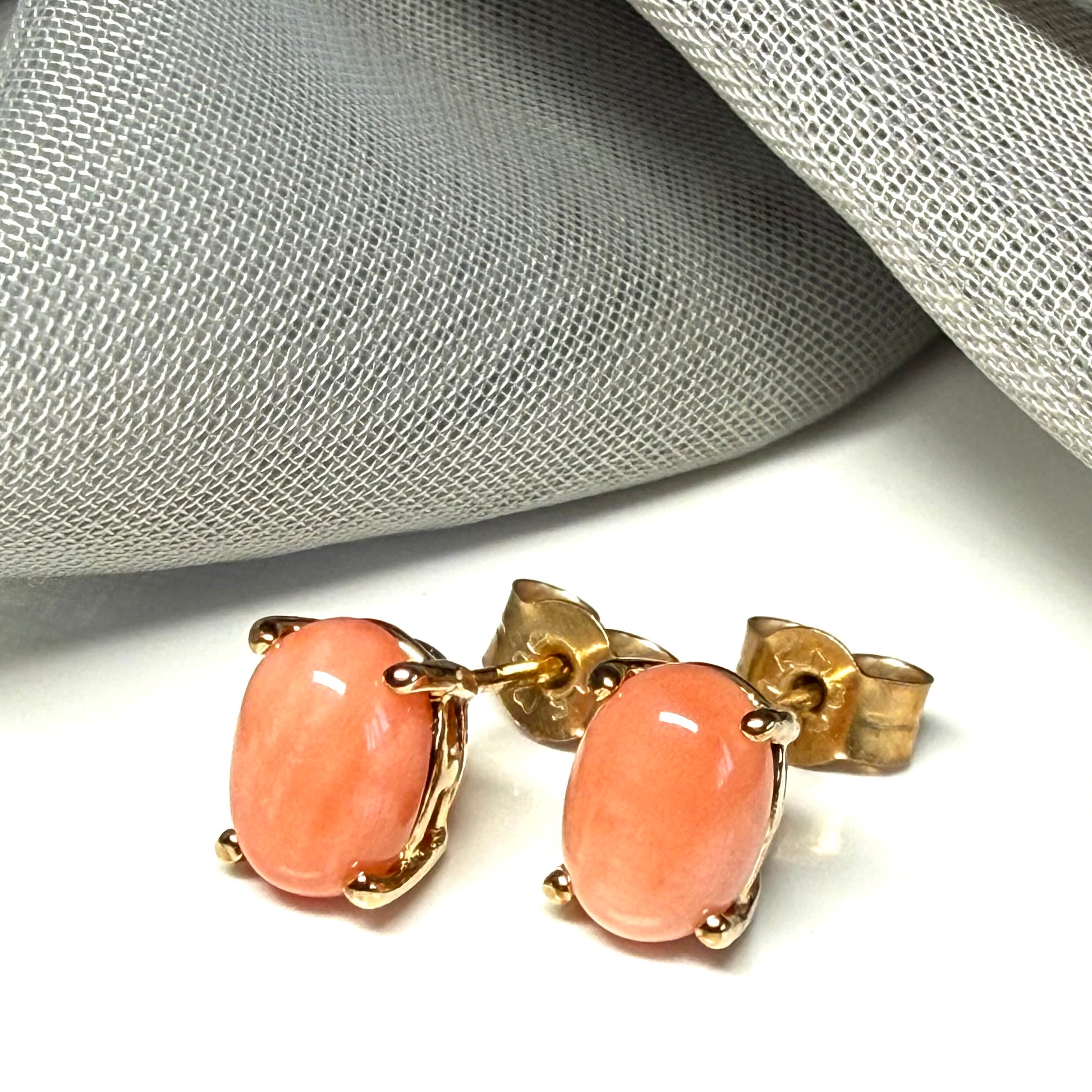 A pair of real coral oval shaped stud earrings yellow gold claw set