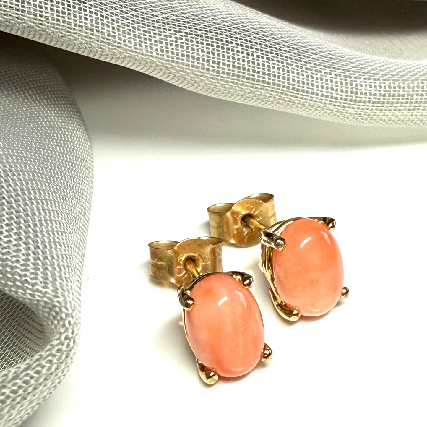 A pair of real coral oval shaped stud earrings yellow gold claw set