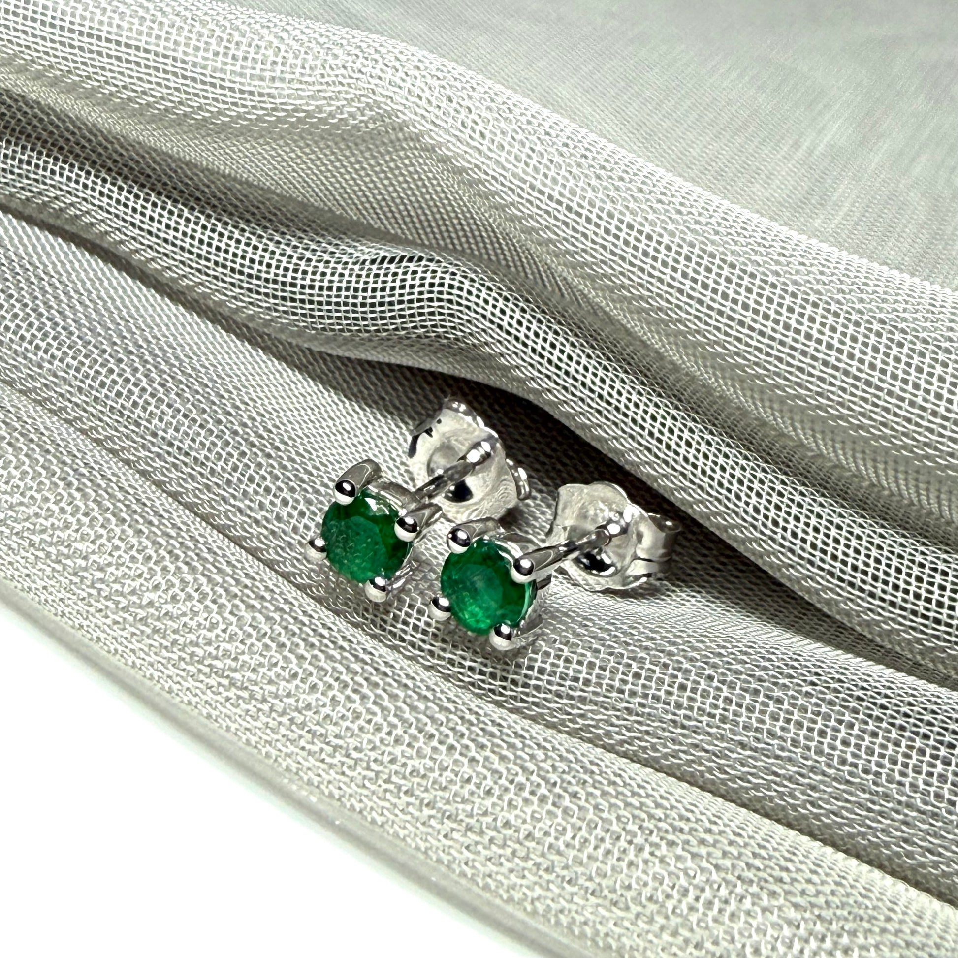 A pair of real green emerald earrings round white gold claw set studs