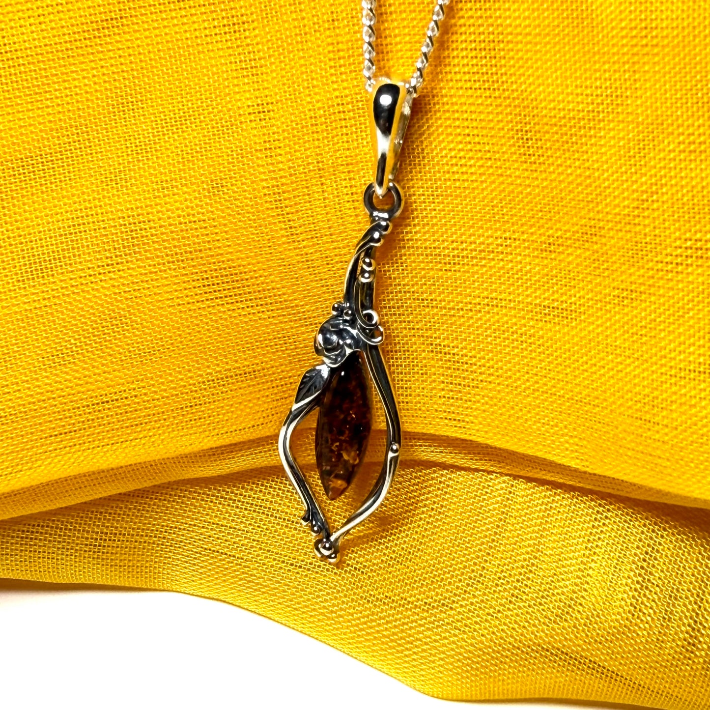 Real amber oval sterling silver necklace with a swirl set fancy patterned open pendant
