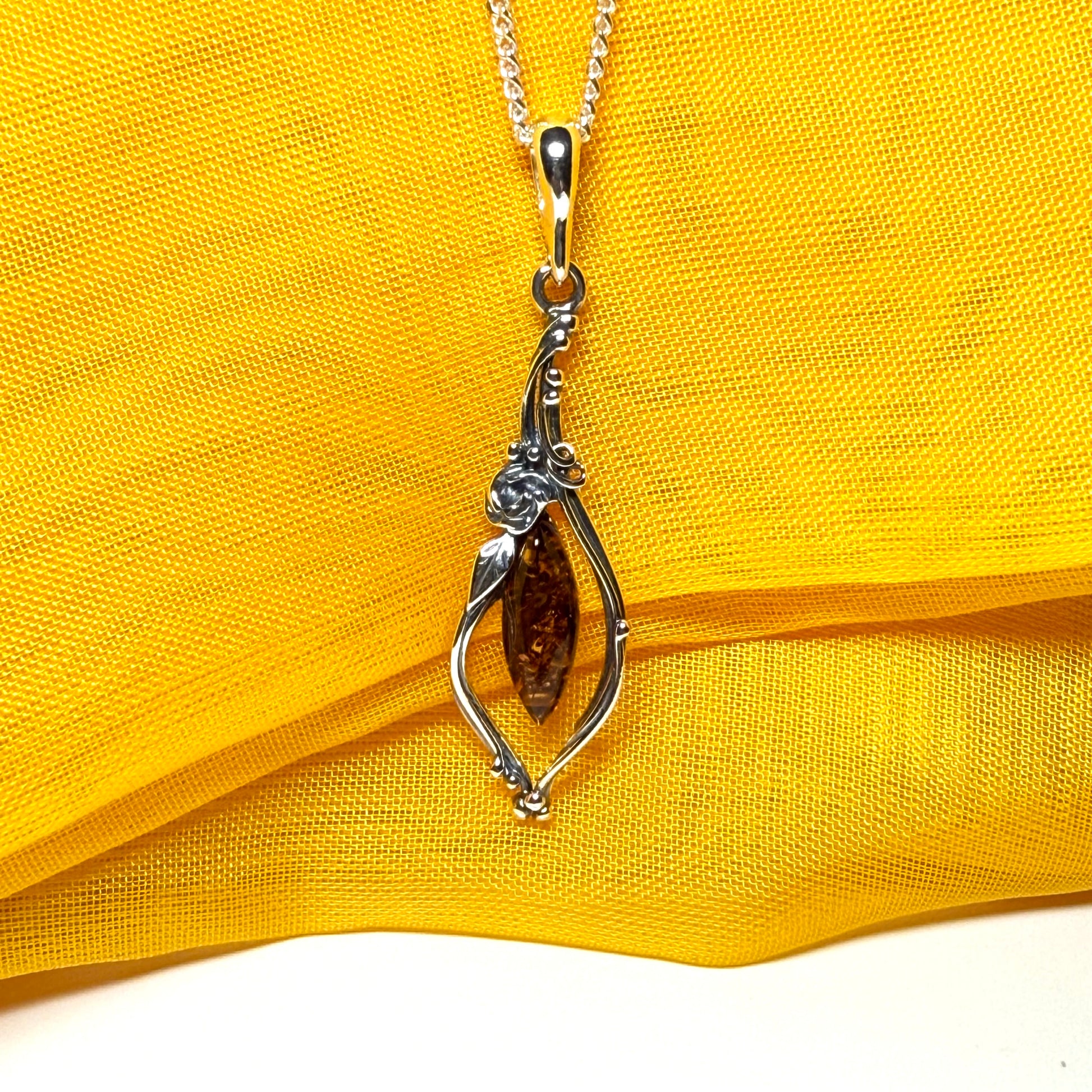 Real amber oval sterling silver necklace with a swirl set fancy patterned open pendant