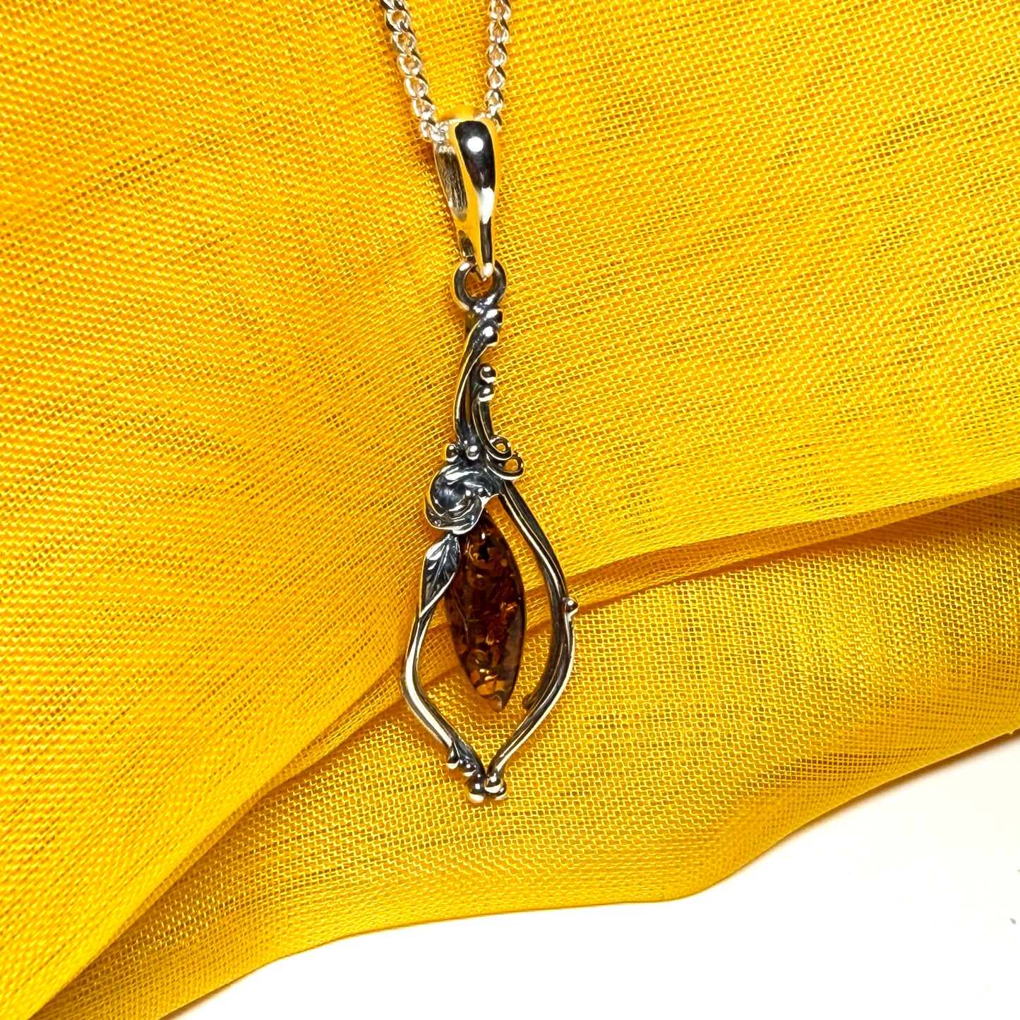 Real amber oval sterling silver necklace with a swirl set fancy patterned open pendant