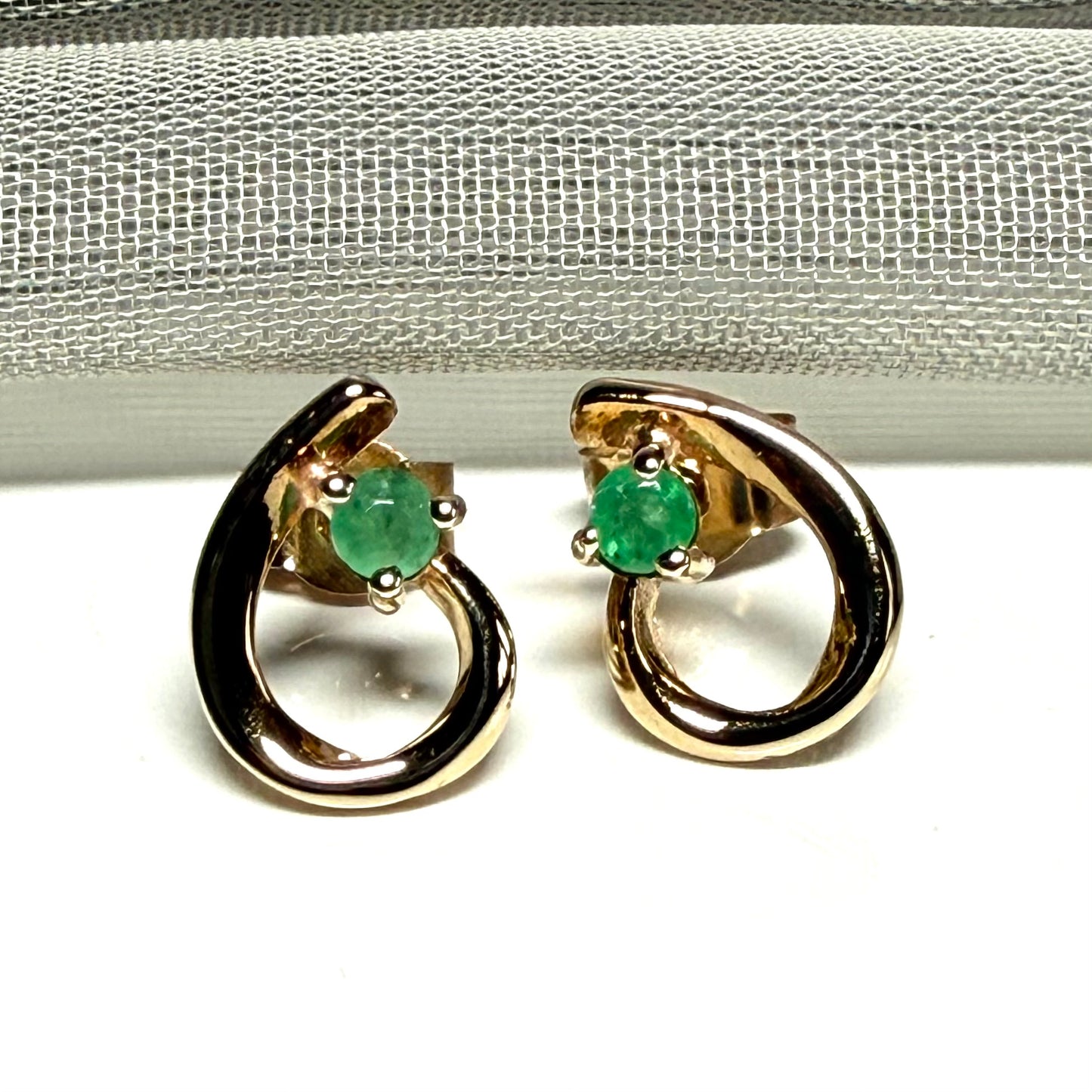 Real emerald pair of stud earrings with a fancy swirl design