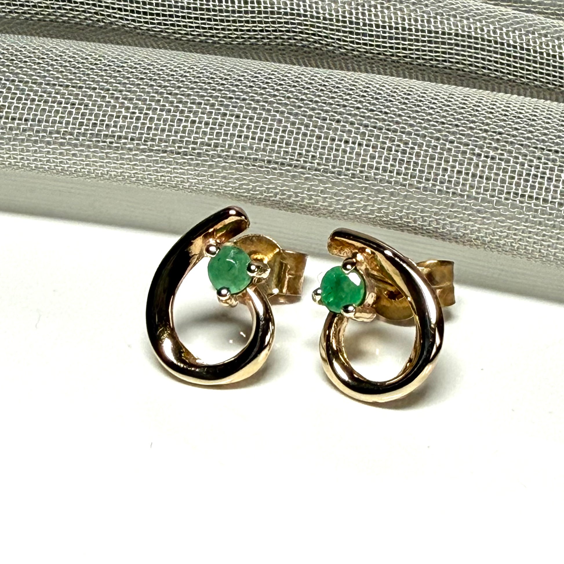 Real emerald pair of stud earrings with a fancy swirl design