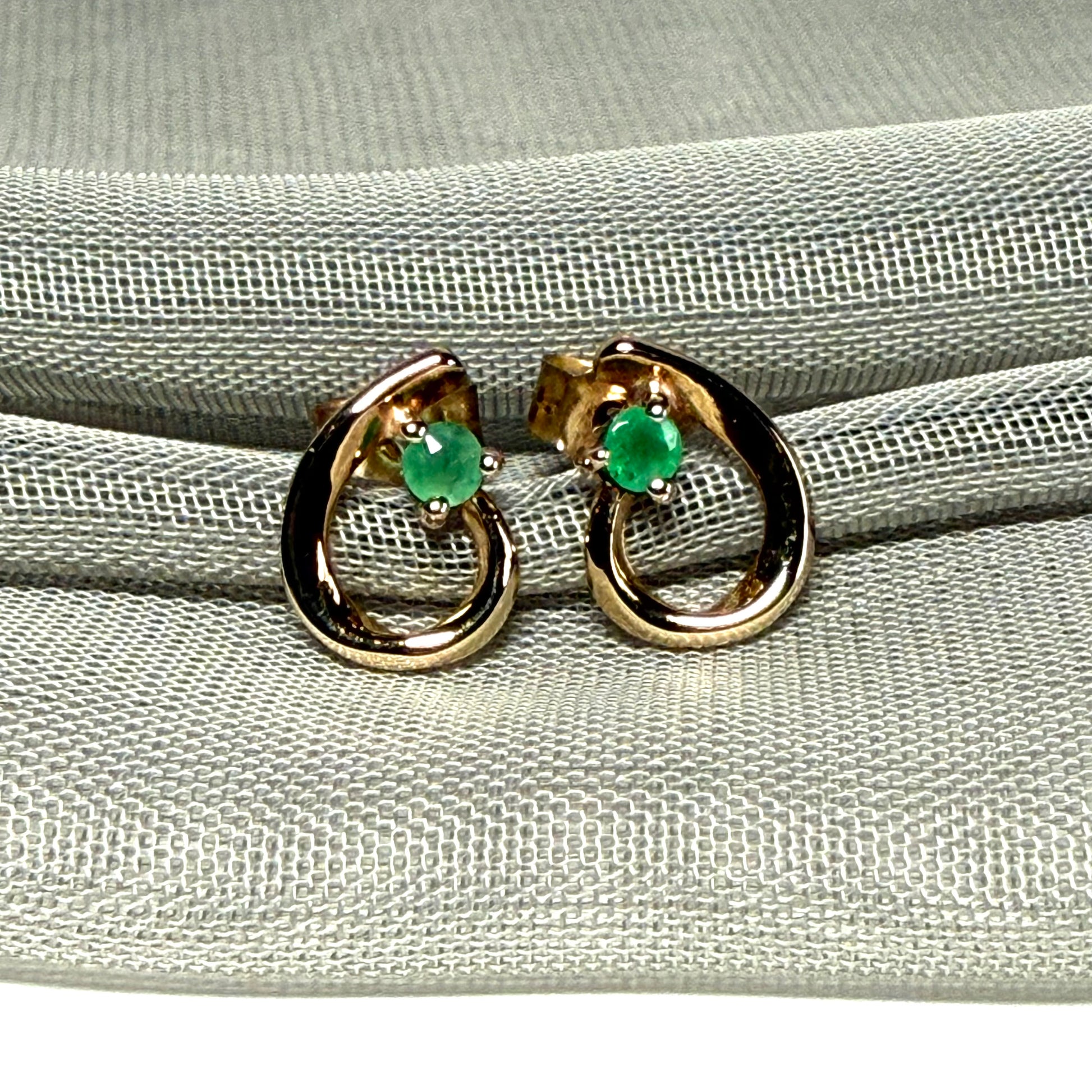 Real emerald pair of stud earrings with a fancy swirl design