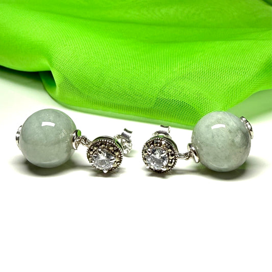 Pair of earrings with green gemstones and silver accents on a white background