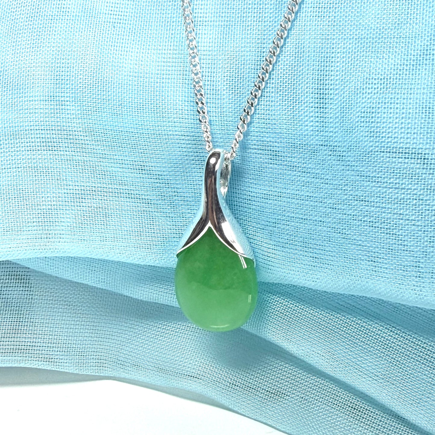 A real green jade necklace in a tear drop or pear shaped with a chain