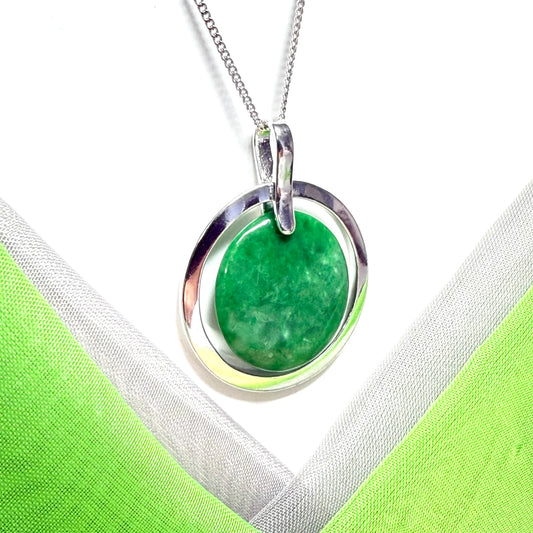 Real green jade stone pendant with silver circle on a white and green fabric background