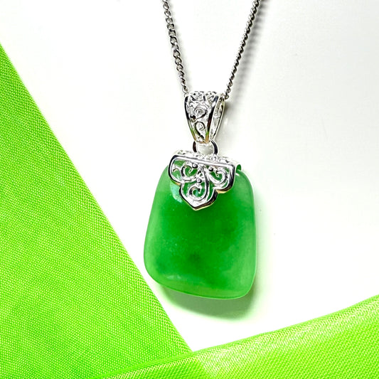 Green pendant necklace on a white background with green fabric
