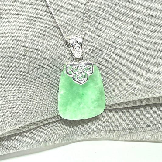 Real green jade pendant necklace on a gray fabric background