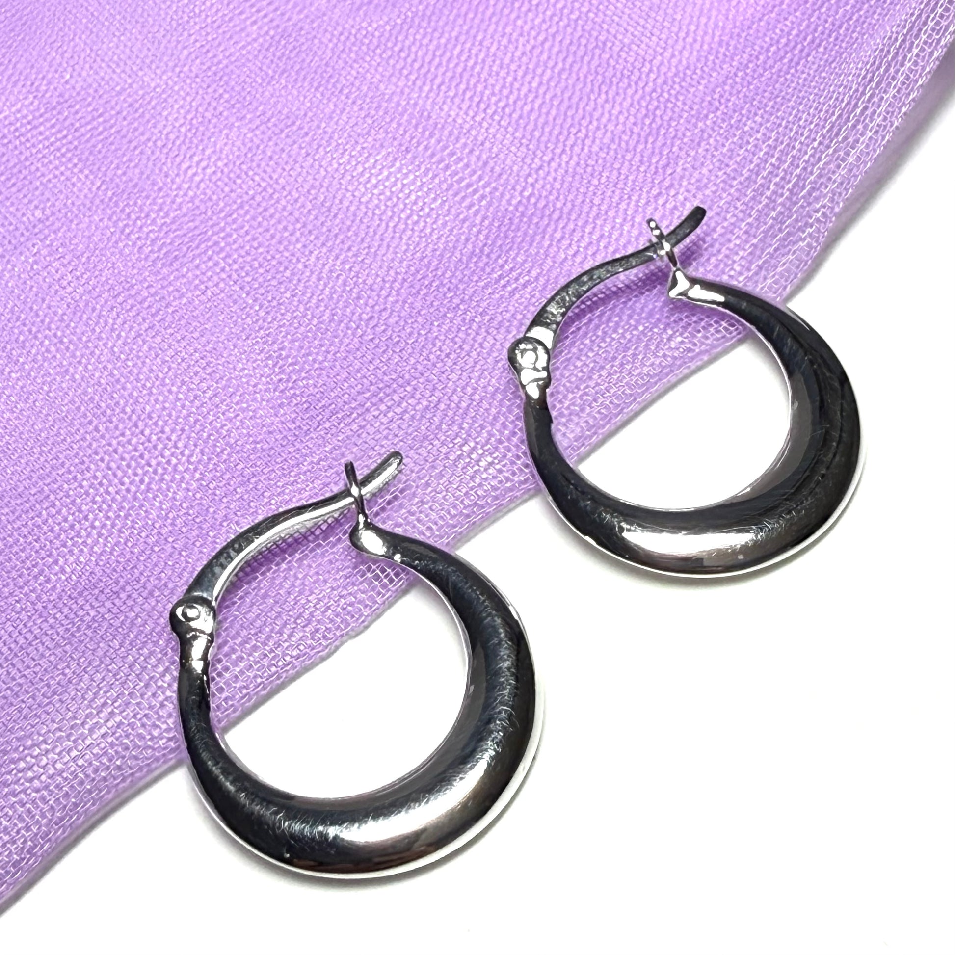 Silver hoop earrings on a purple fabric background