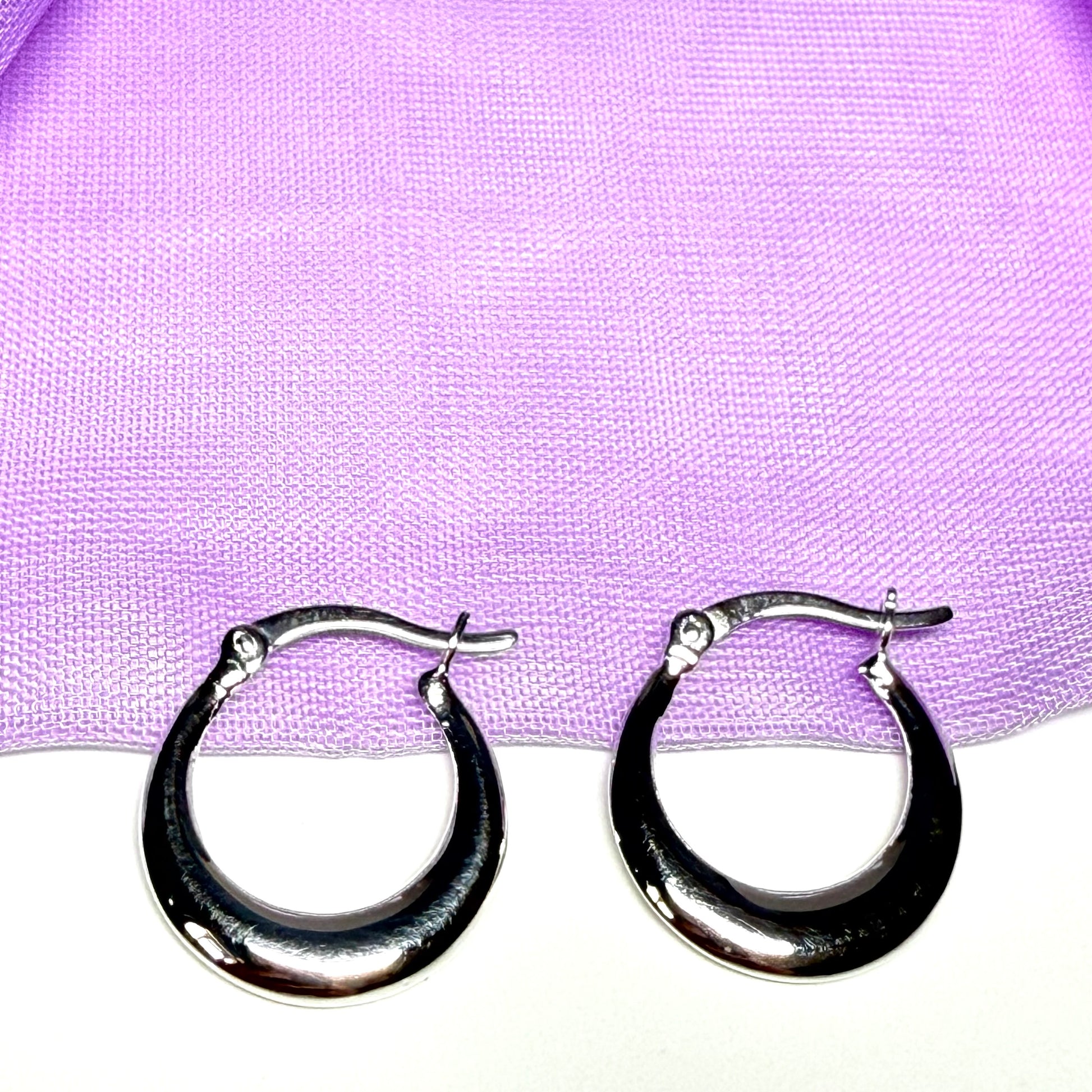 Silver hoop earrings on a purple fabric background